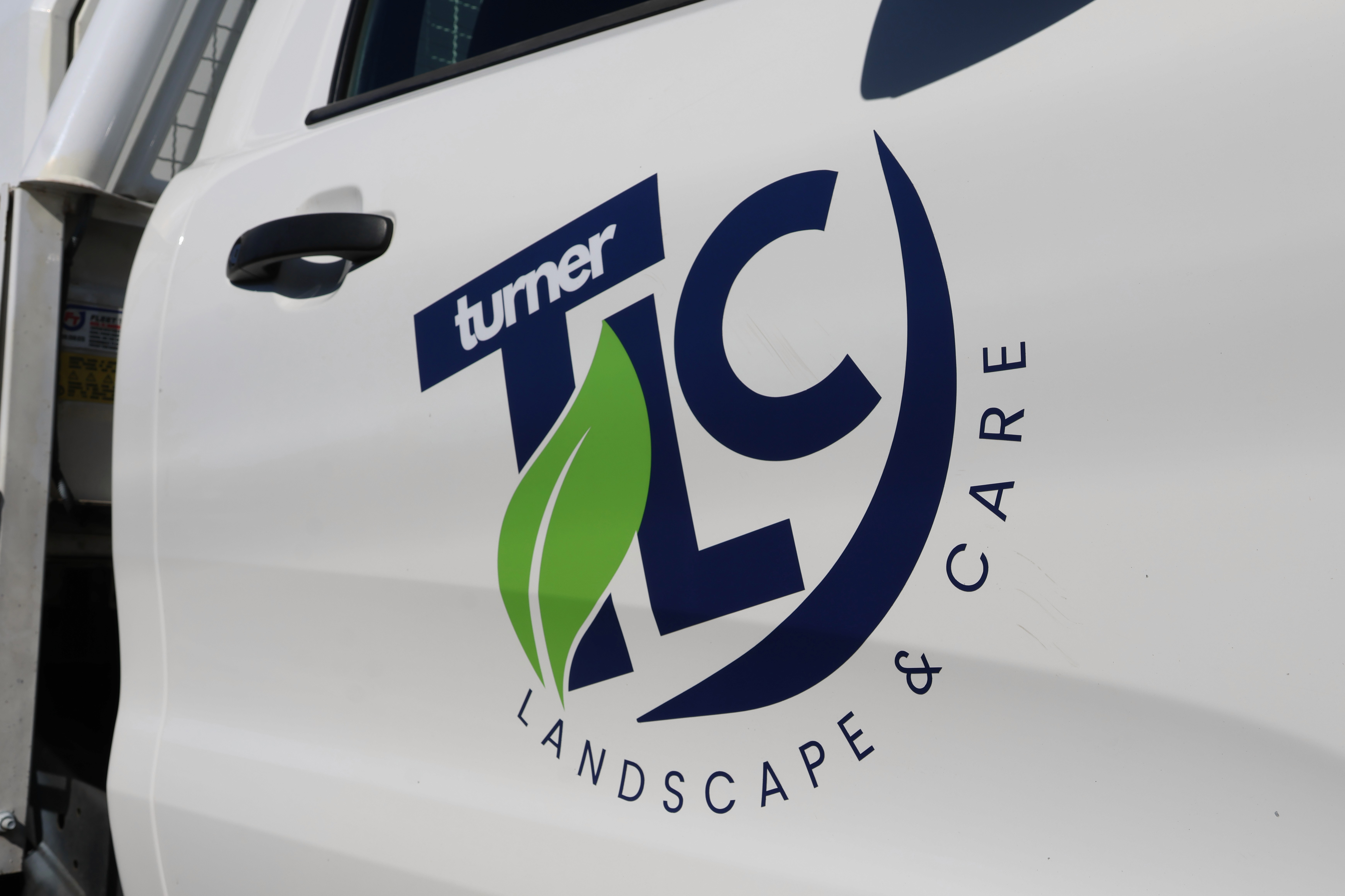 Turner TLC Landscape & Care logo with a green leaf on a white vehicle.