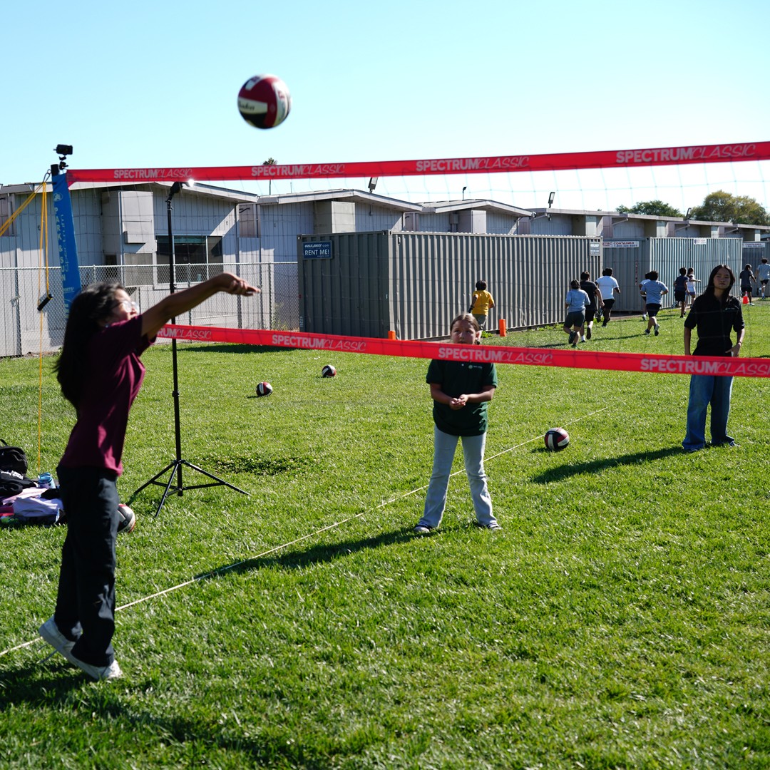 students playing volleyball outdoors during a school enrichment sports activity on the field