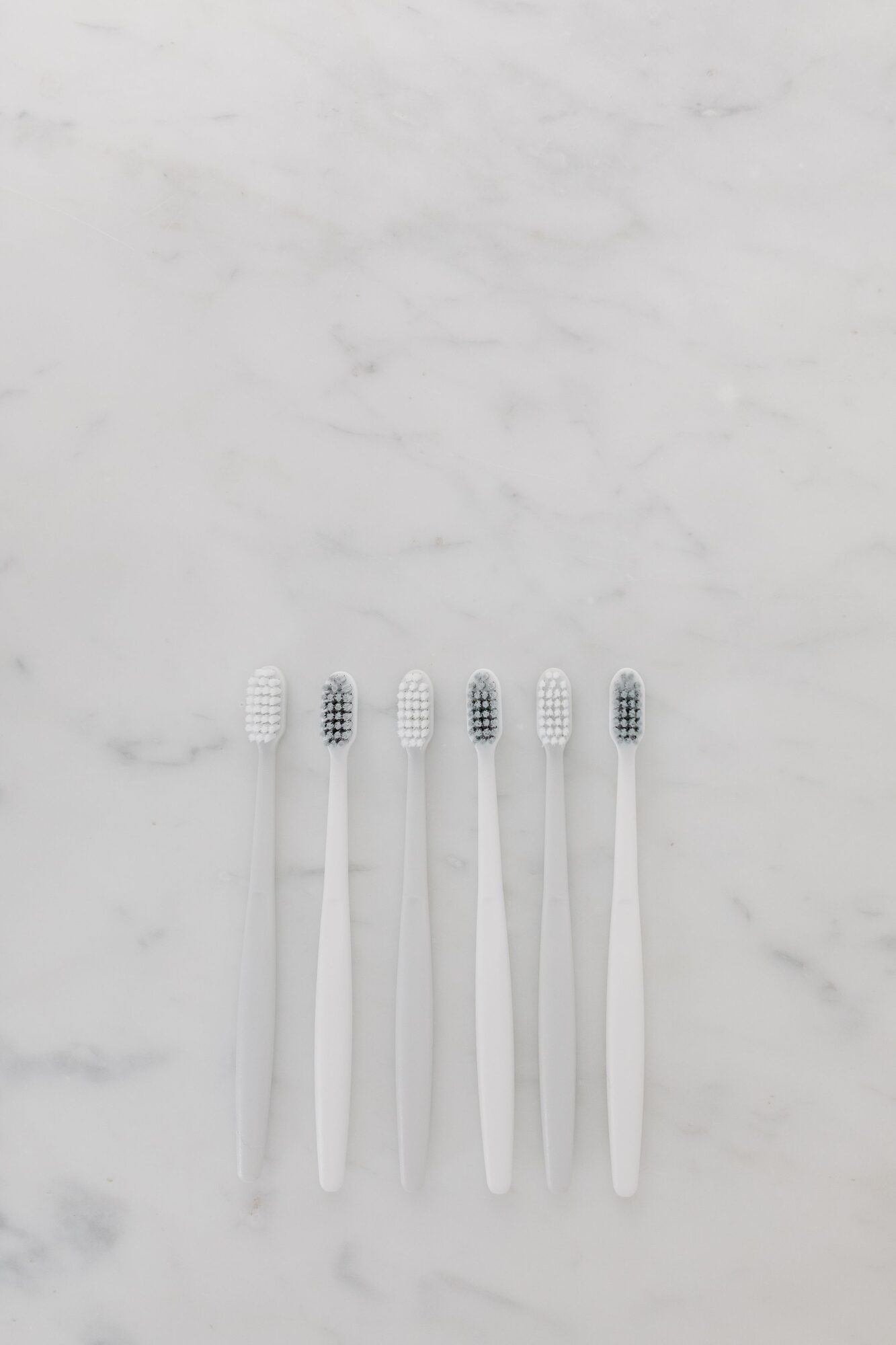 A row of white toothbrushes resting on pale marble