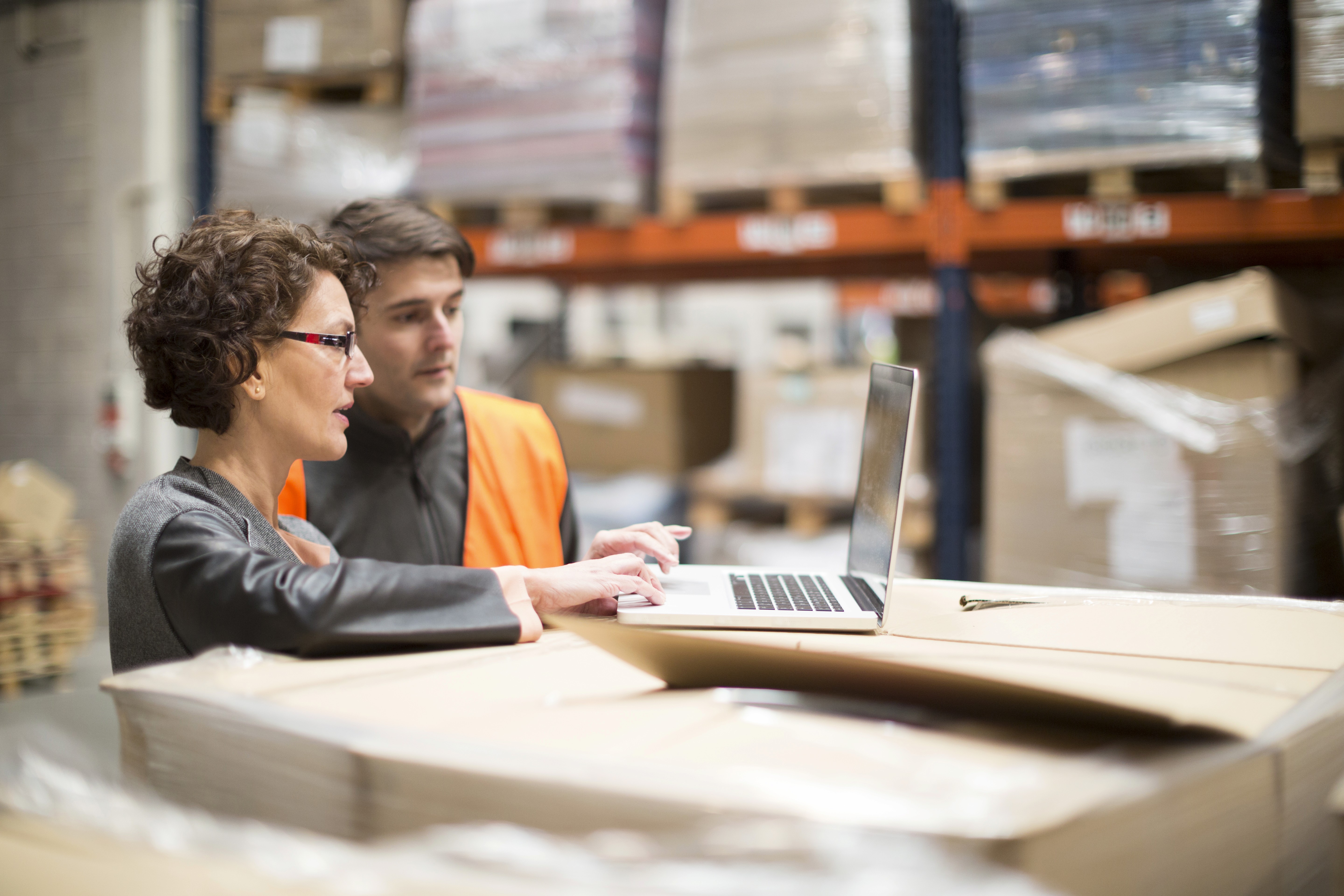 Man and woman look at laptop in warehouse