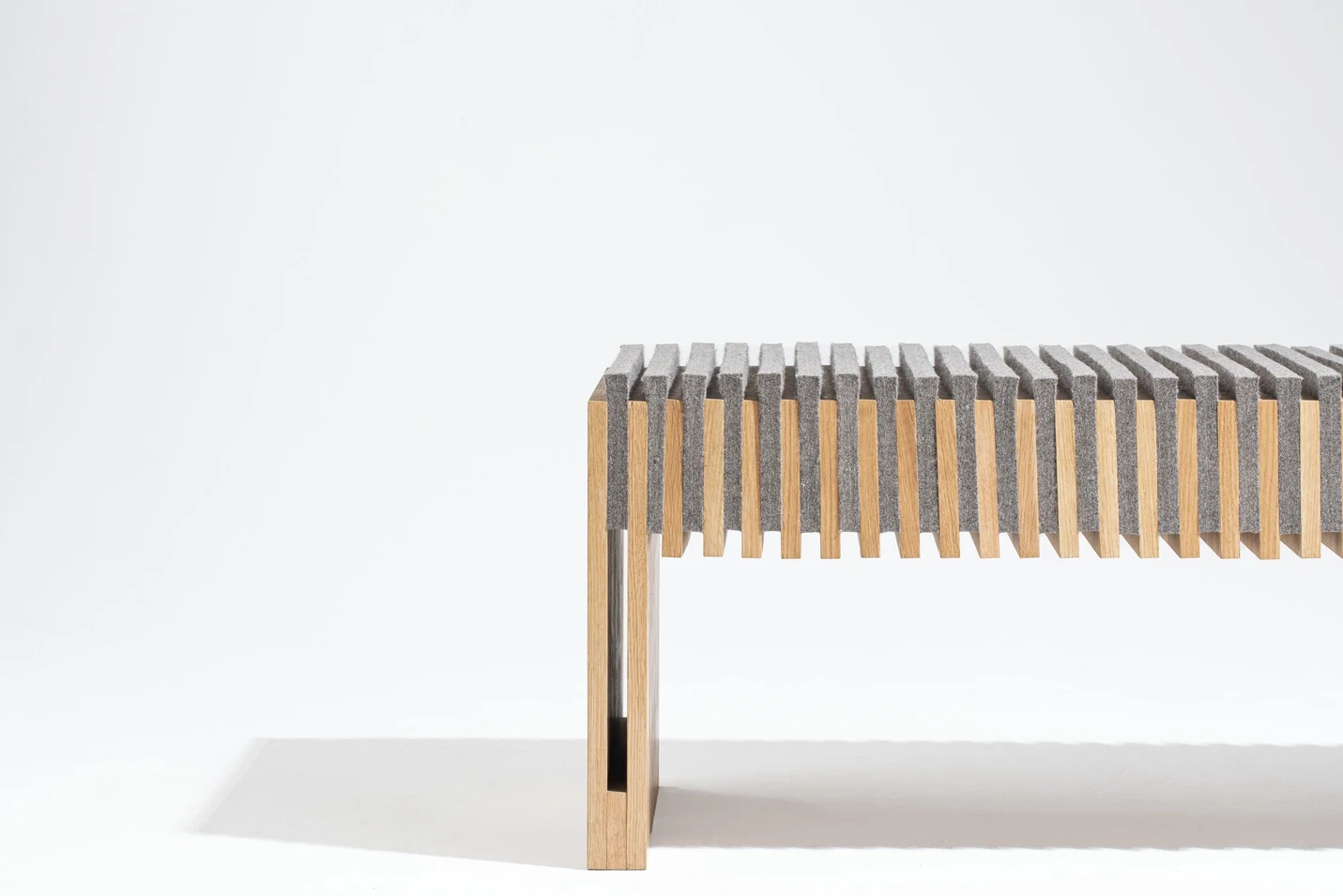 Banc design minimaliste en bois clair, vue en perspective trois-quarts.