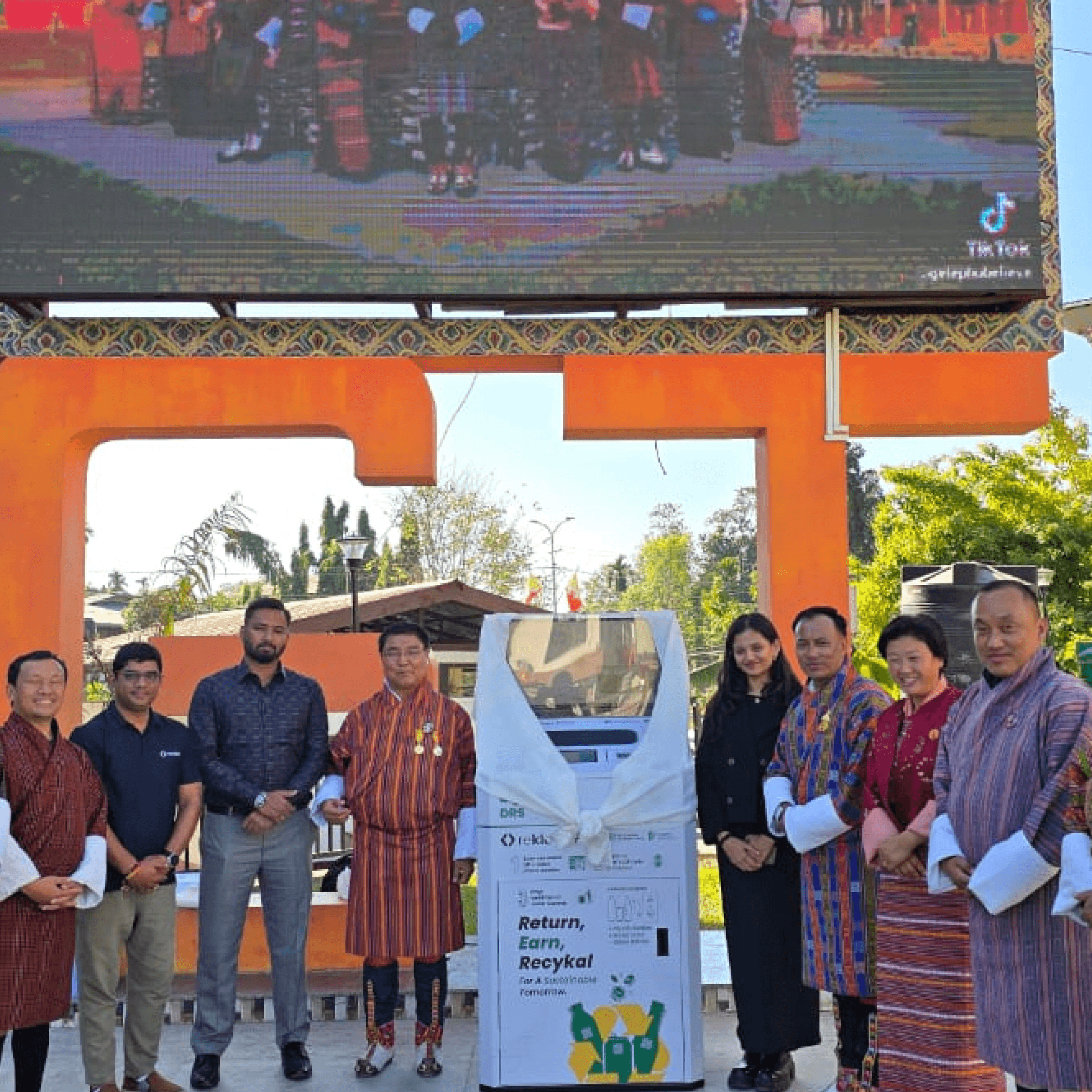 Woman in red outfit poses by a red telephone booth.