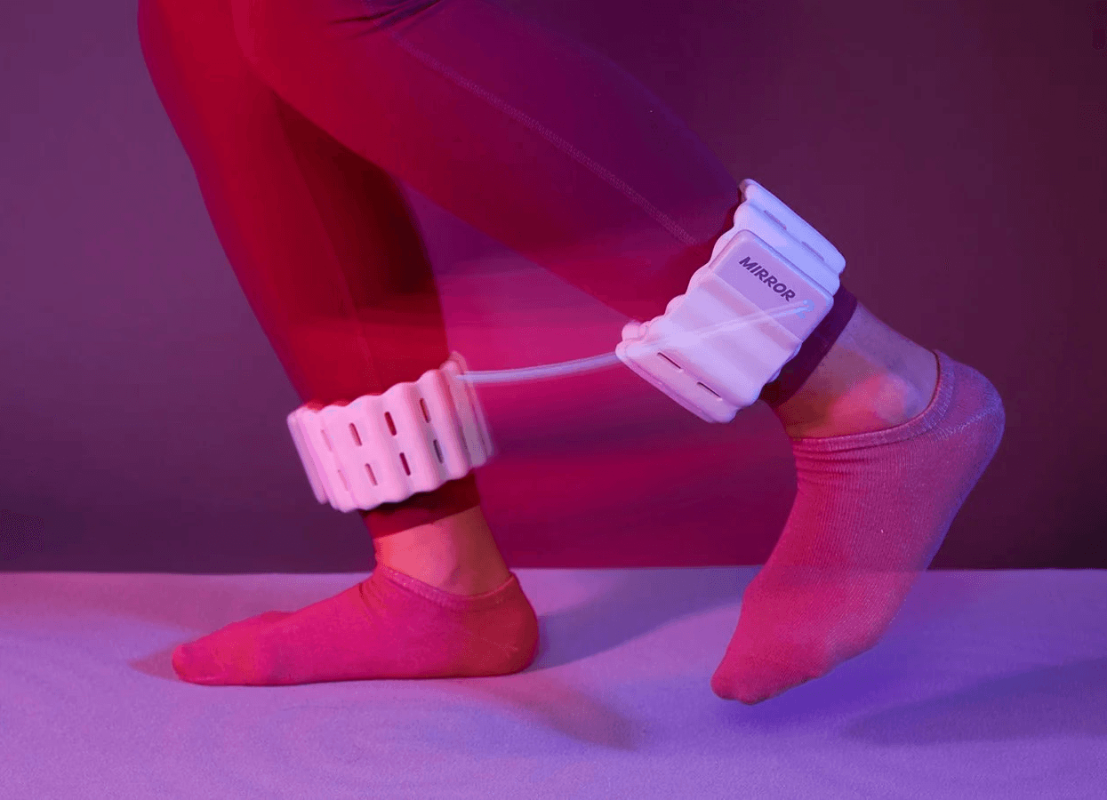 Person wearing Mirror ankle weights against a pink background