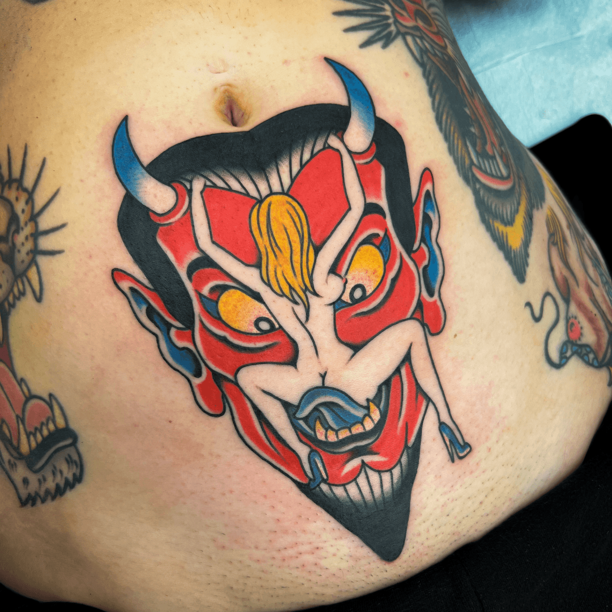 large color tattoo of a devil head and a pin-up girl