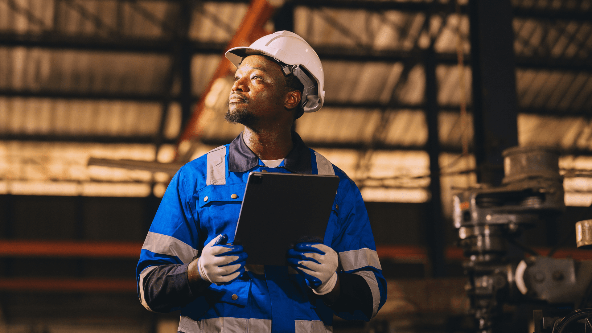 Facilities engineer conducting a site inspection and reviewing building systems using a digital tablet in an industrial environment.