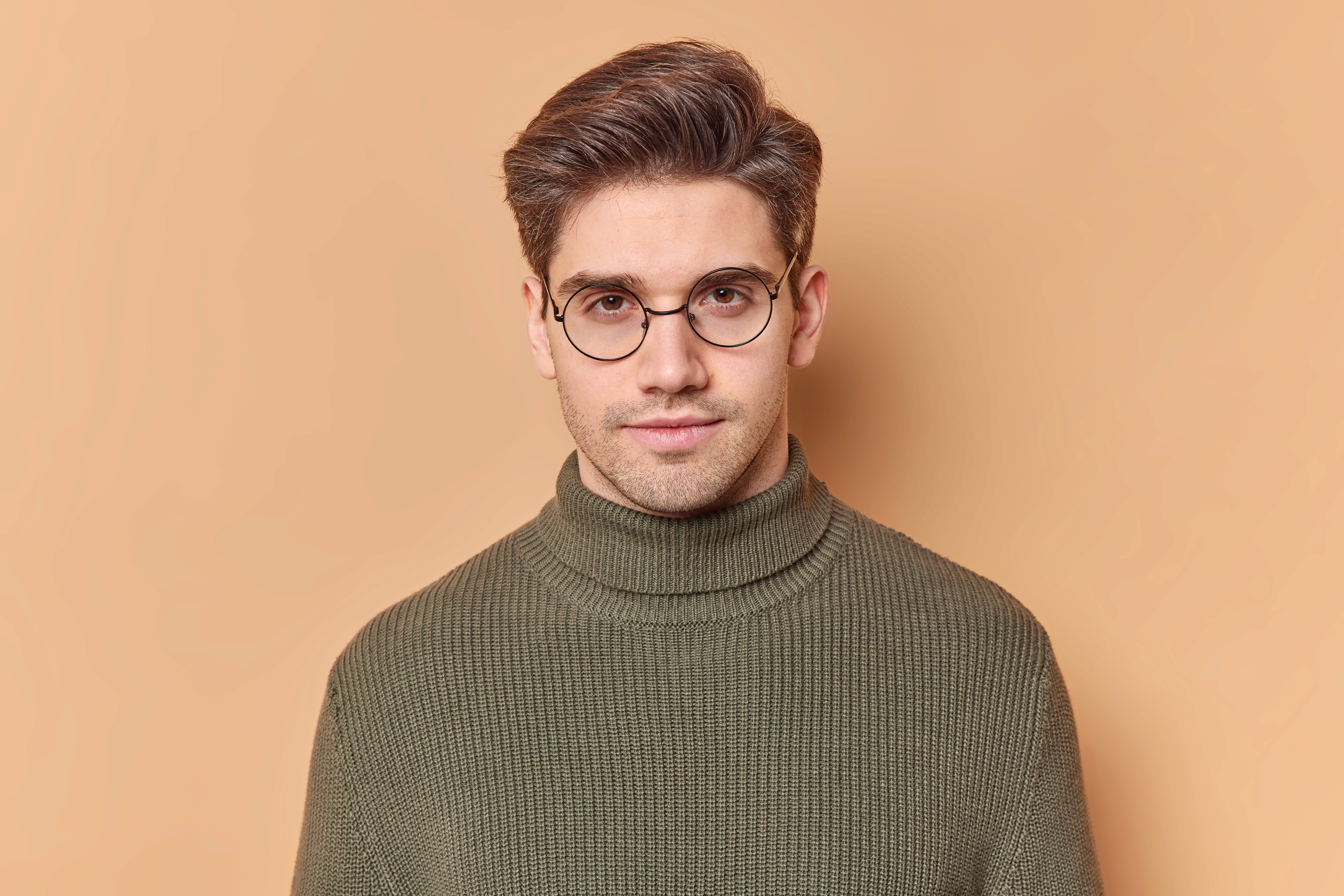Person wearing glasses standing against a yellow background.