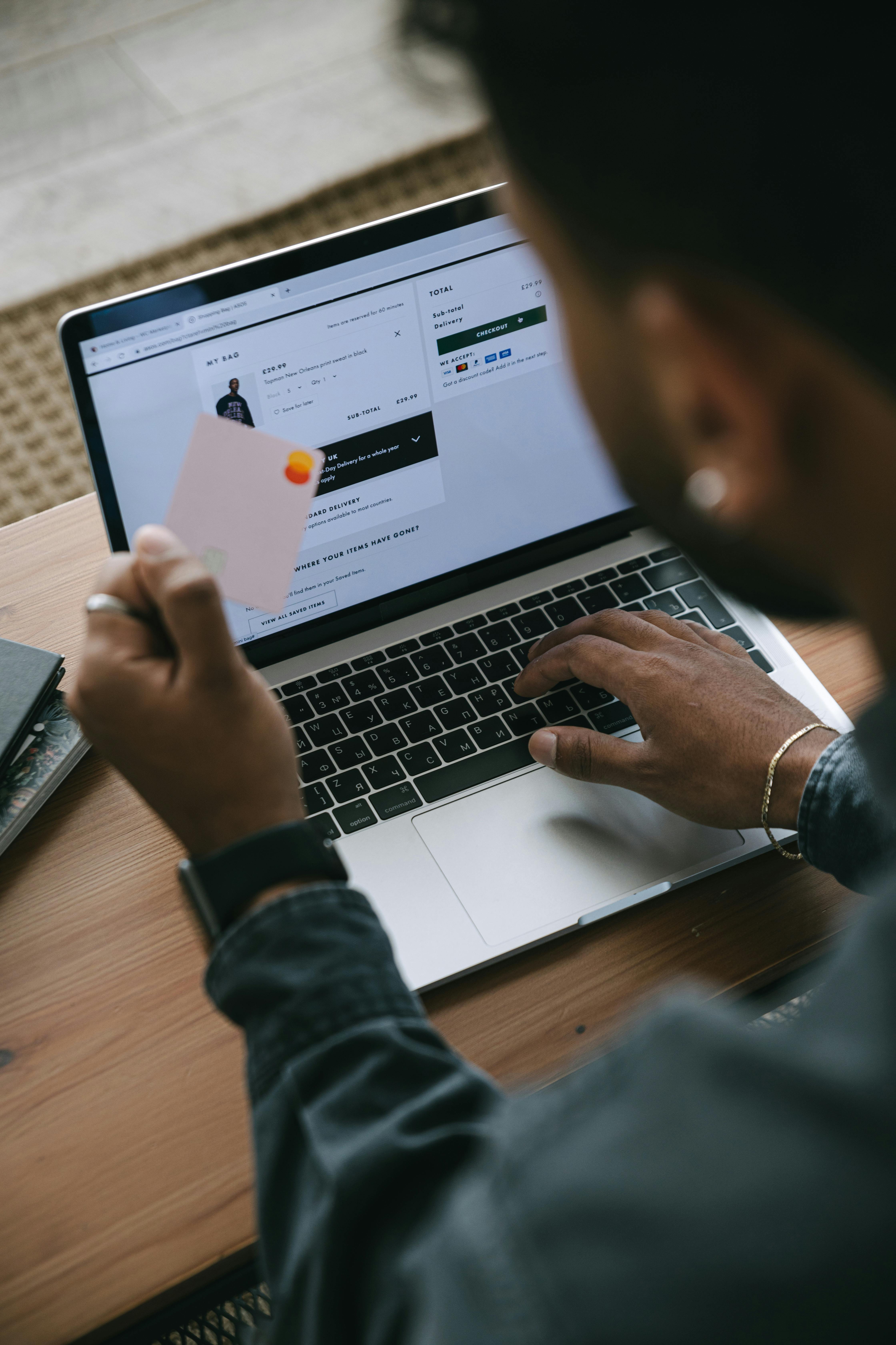 Man holding a credit card while completing an online checkout on a laptop, representing e-commerce purchase intent and conversion.