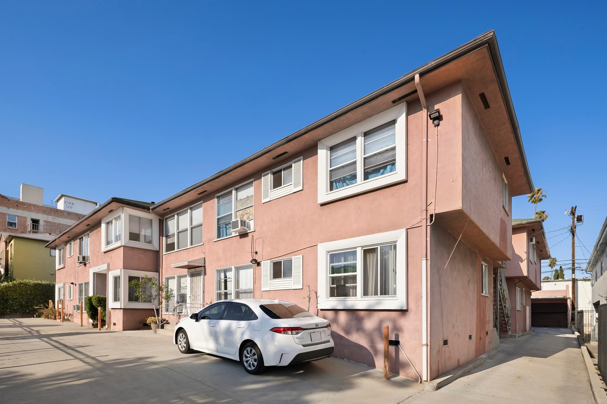 1640 N Harvard multi-family residential building with peach facade, white-trimmed windows, and parked white vehicle