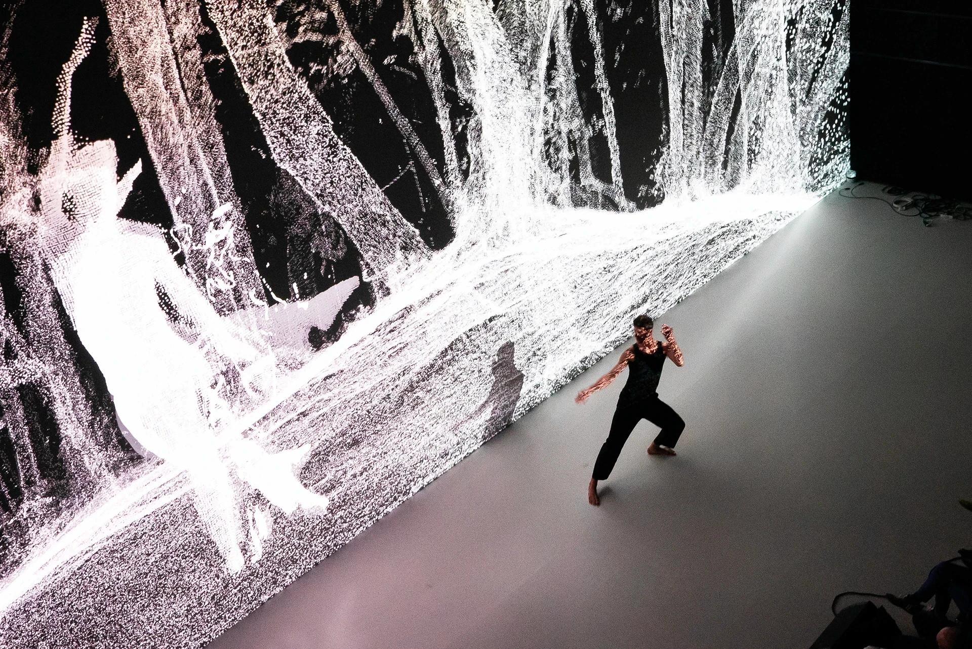 Dancer performs in front of a large projected digital art installation.