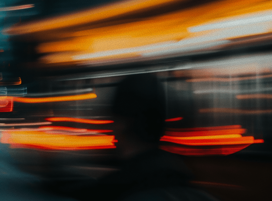 A person standing still as a blurred train passes, creating dynamic light streaks.