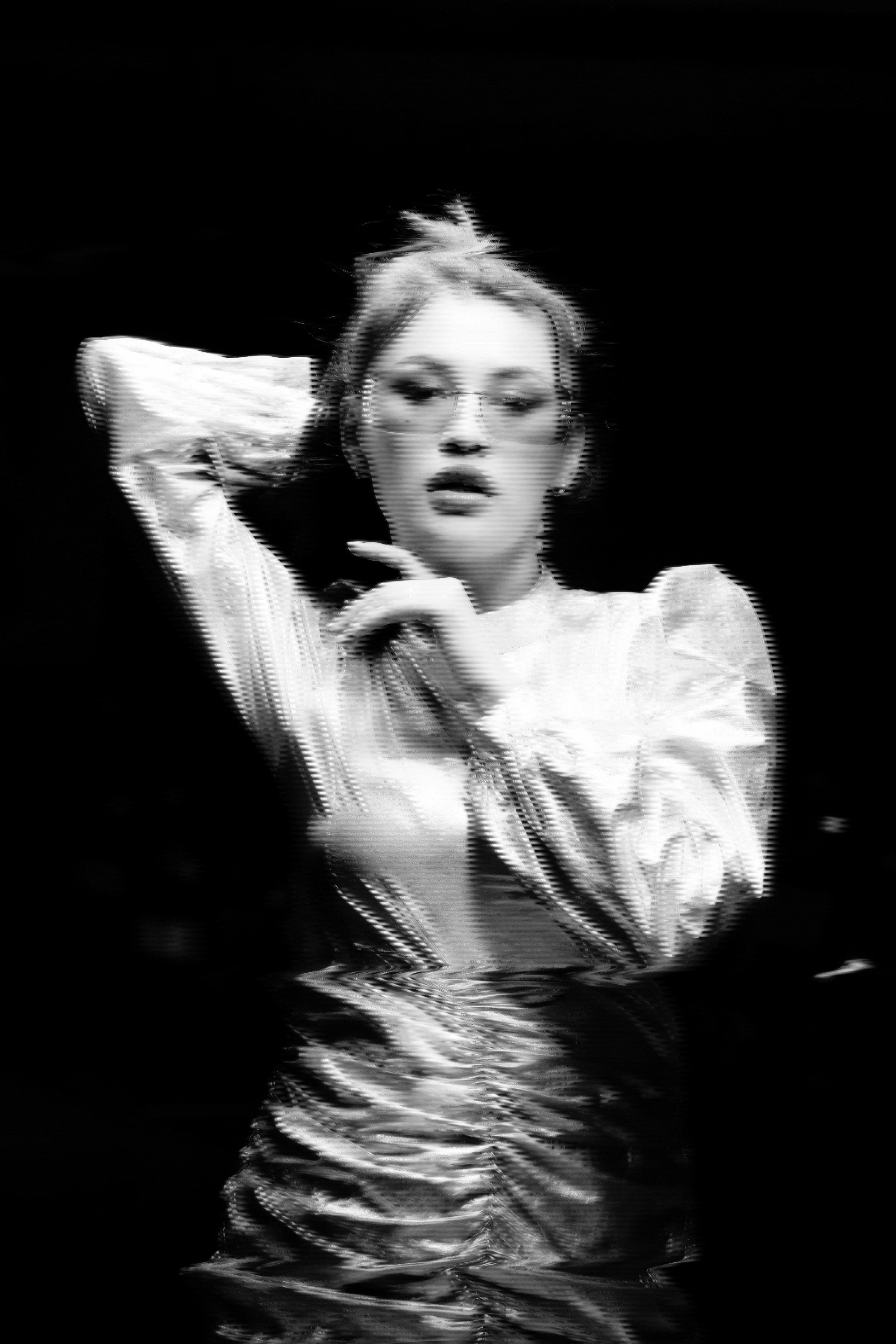 Woman in stylish outfit posing with hands in hair.