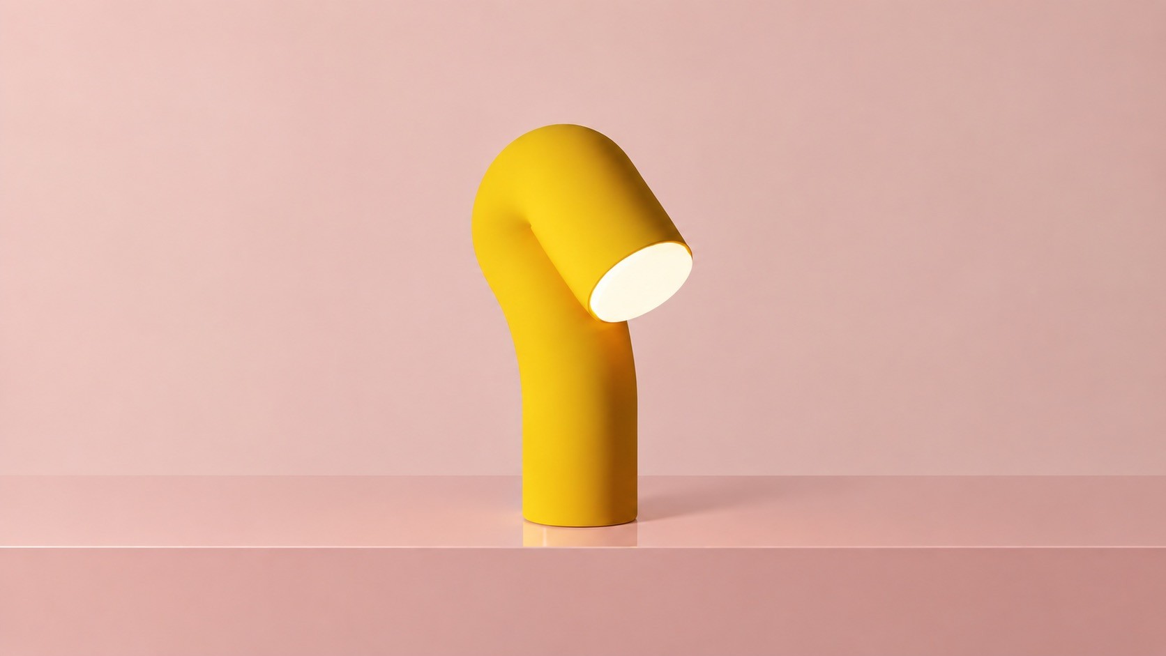 Yellow table lamp shaped like a bent tube with a glowing disc at its end, on a pink ledge against a pink wall