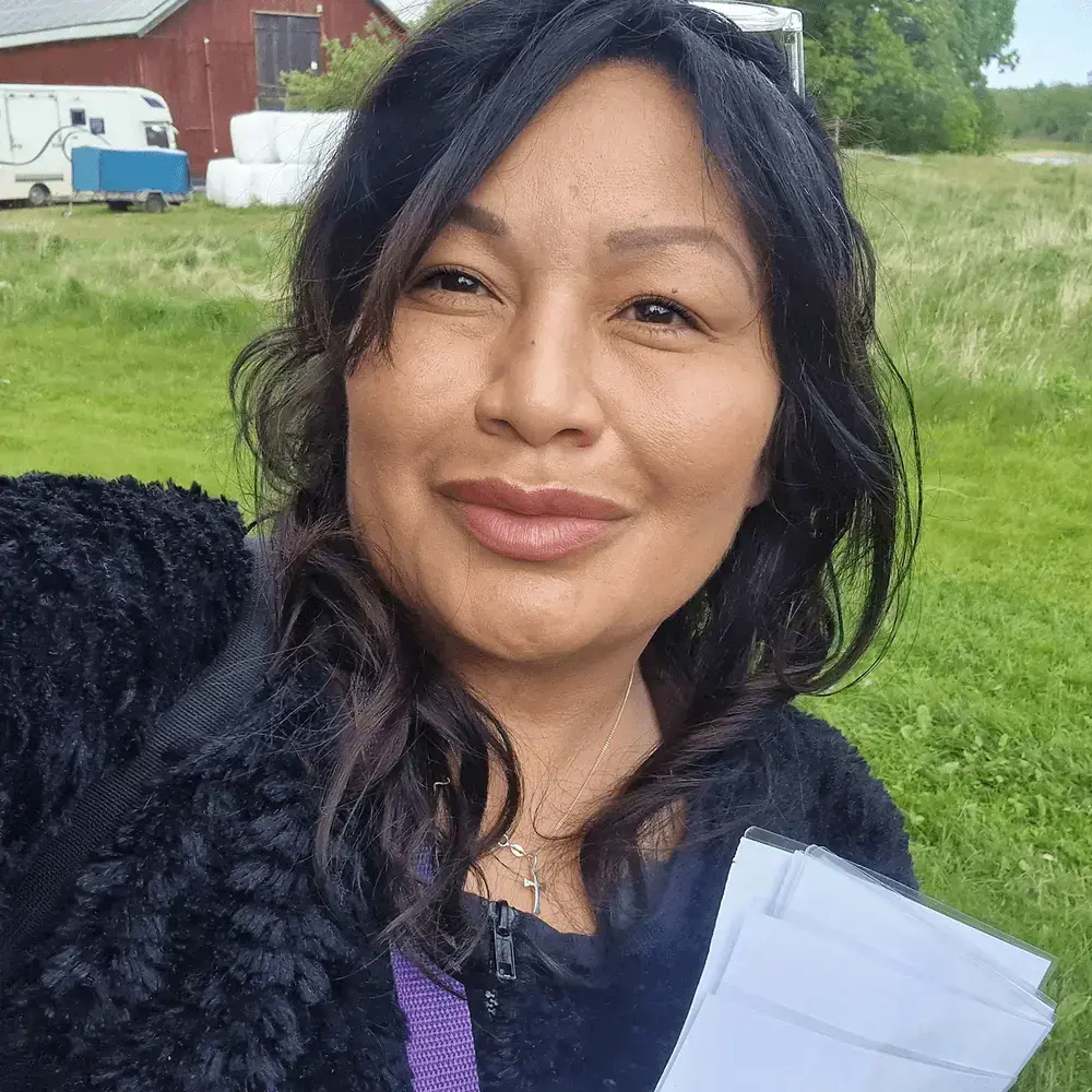 Grundare Linda Åkerman utomhus håller dokument och tittar mot kameran.