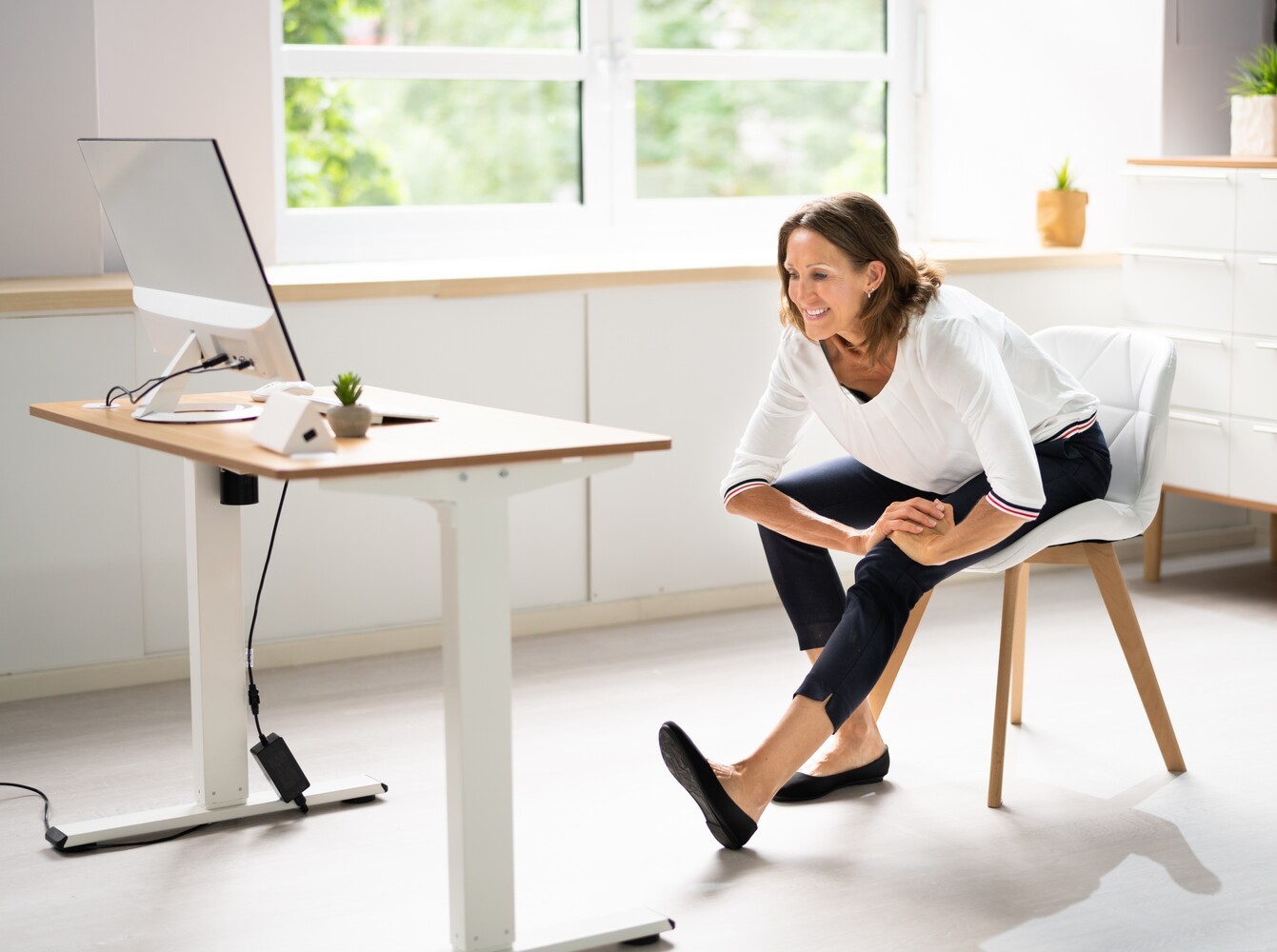 middle-aged woman doing a chair workout for weight loss in her home office during her workday