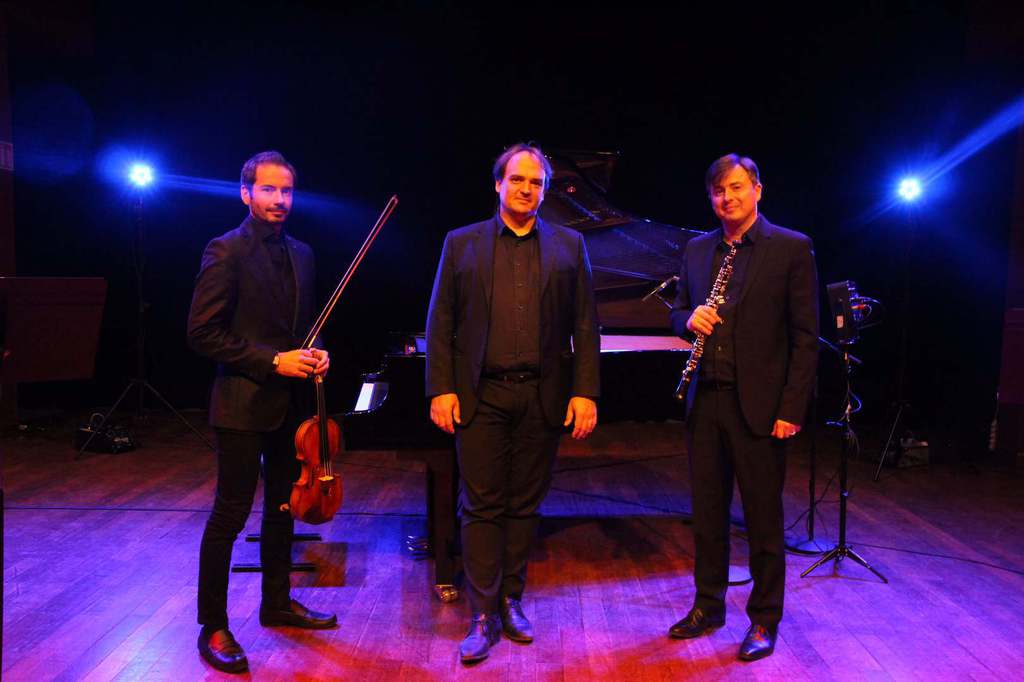 trois musiciens sur scene posant pour une photo