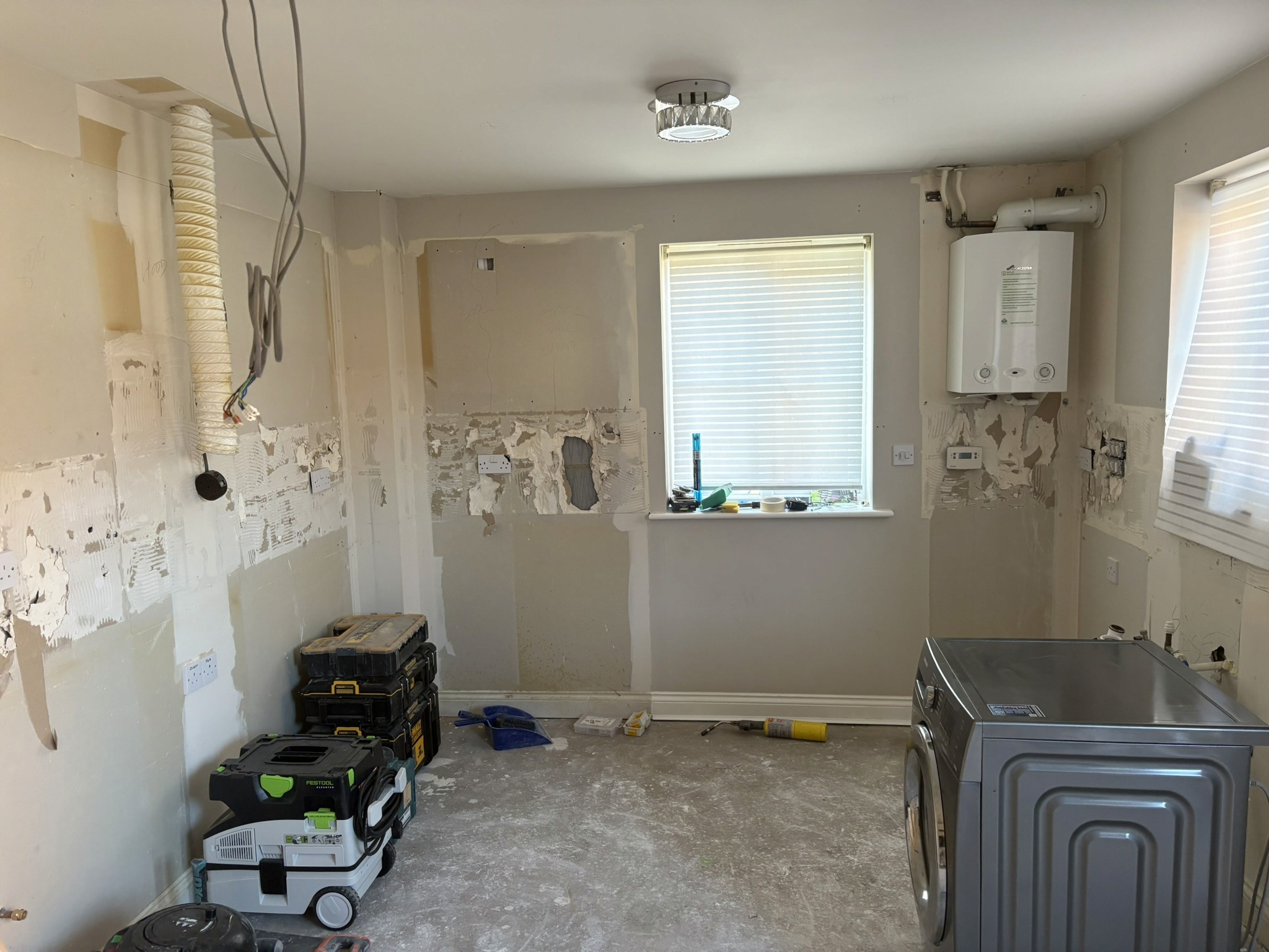 Kitchen renovation in progress, with units removed and exposed wall surfaces and service points.