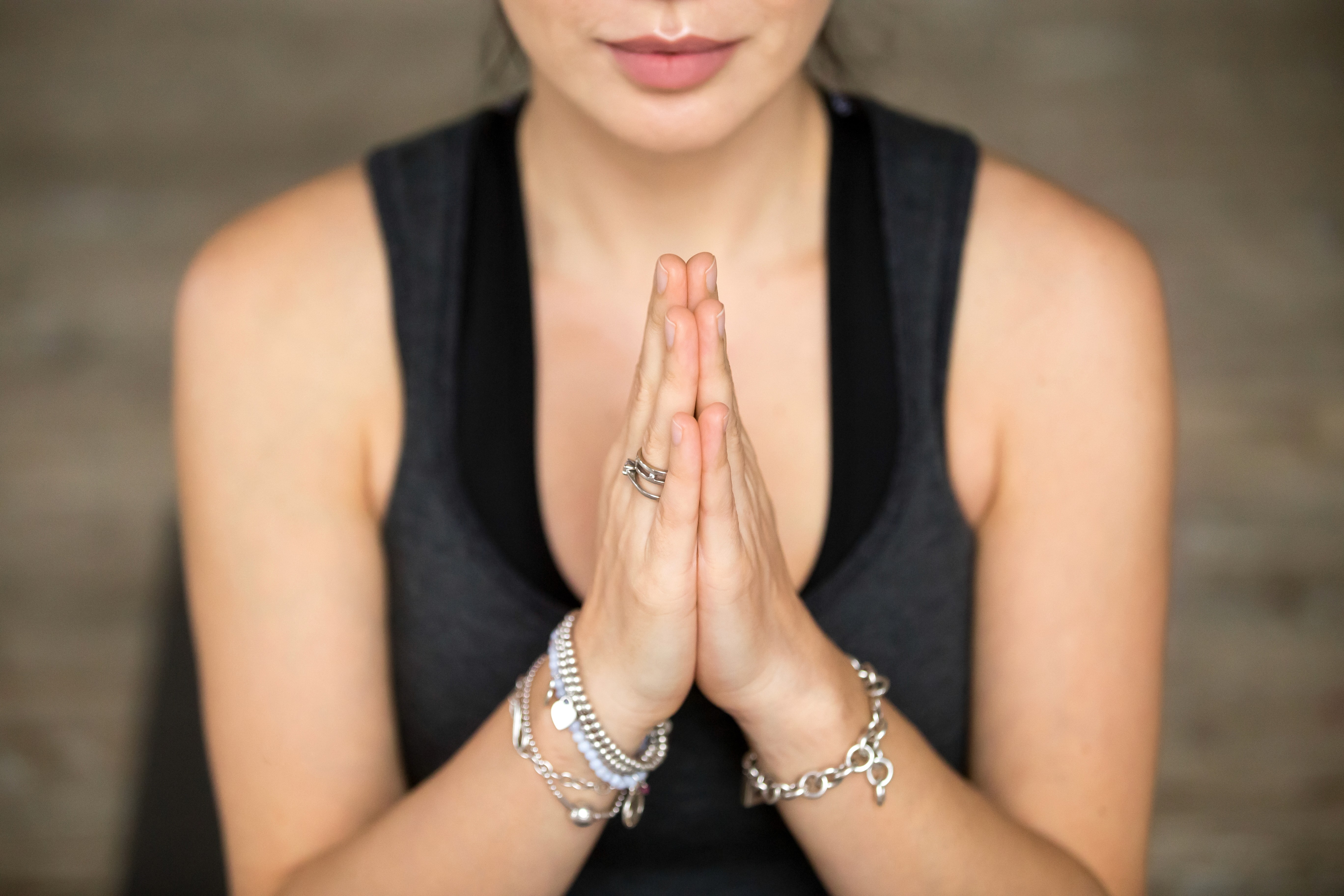 Um close-up das mãos de um praticante a segurar um mala (rosário de meditação) ou com os dedos em mudra (gesto de mão).