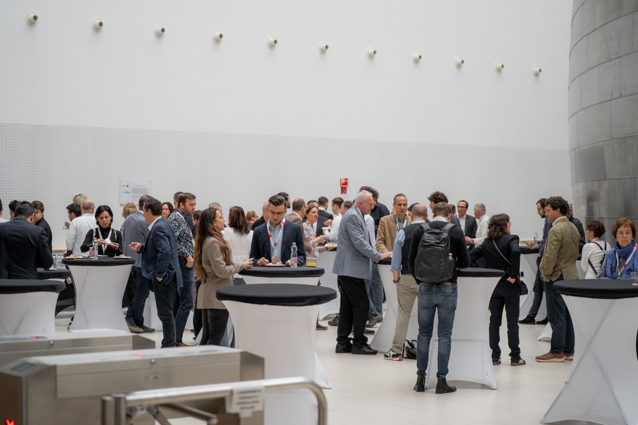 People networking at standing tables with white cloths