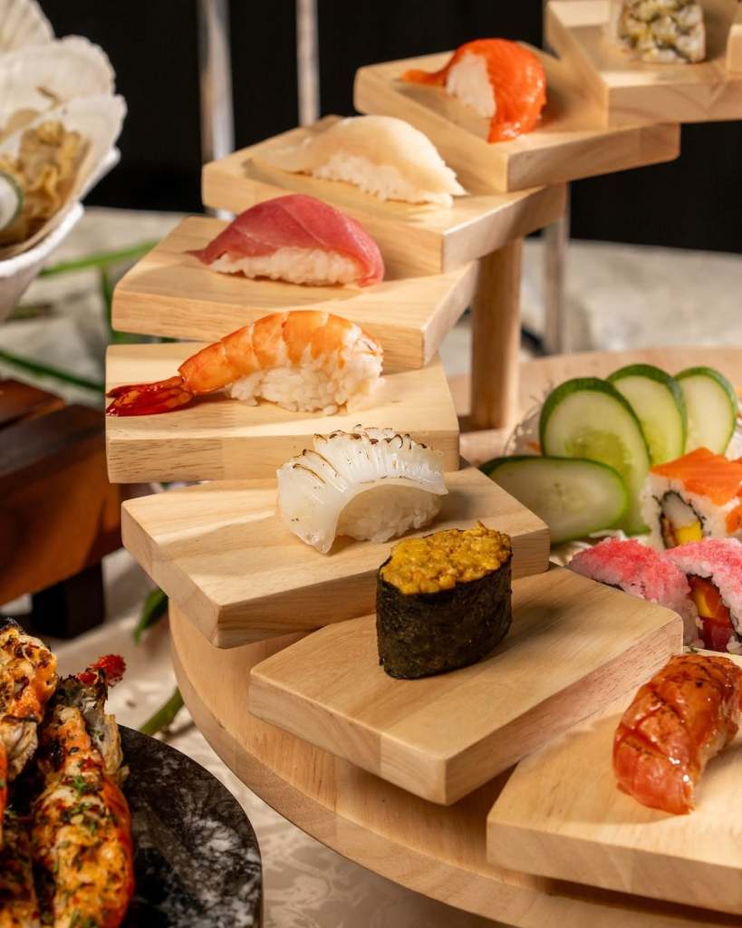 An assortment of sushi displayed on a wooden platter, featuring various types of sushi including shrimp, tuna, and salmon, arranged in an appealing manner.