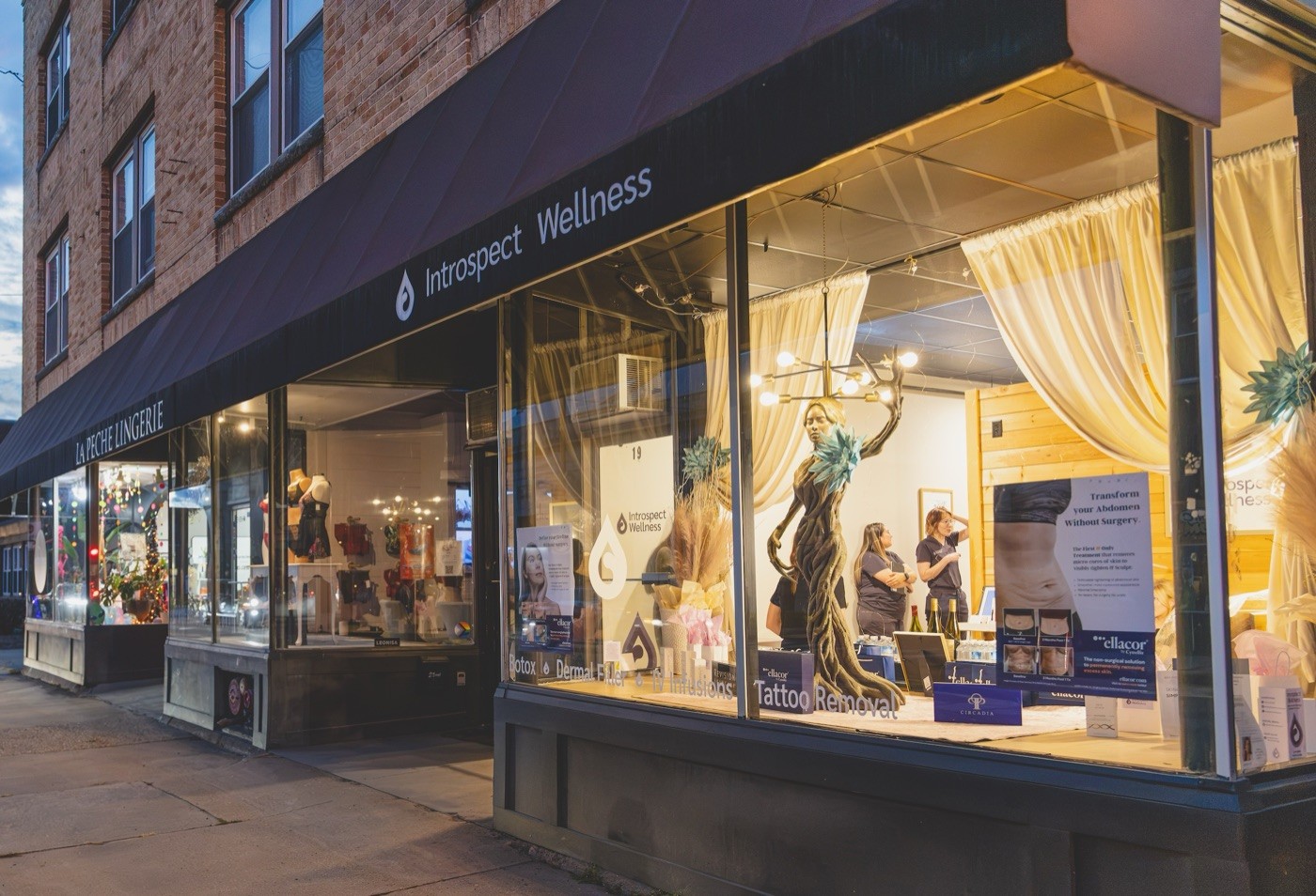 Introspect Wellness storefront at dusk with the lit display window
