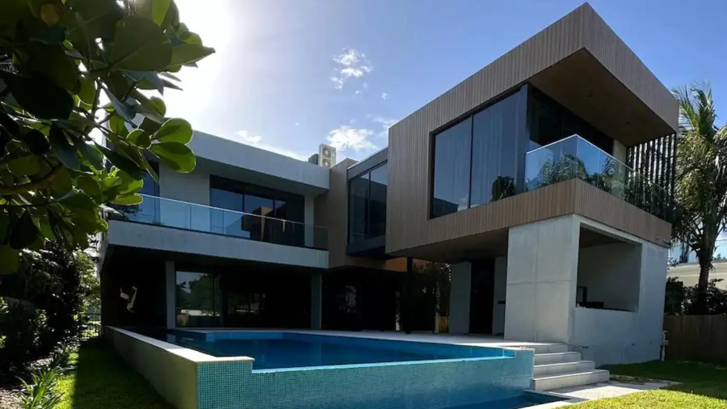 Contemporary two-story residence with infinity pool, wood-clad cantilevered volumes, and glass railings designed by Atelier International in South Beach, Miami Beach.