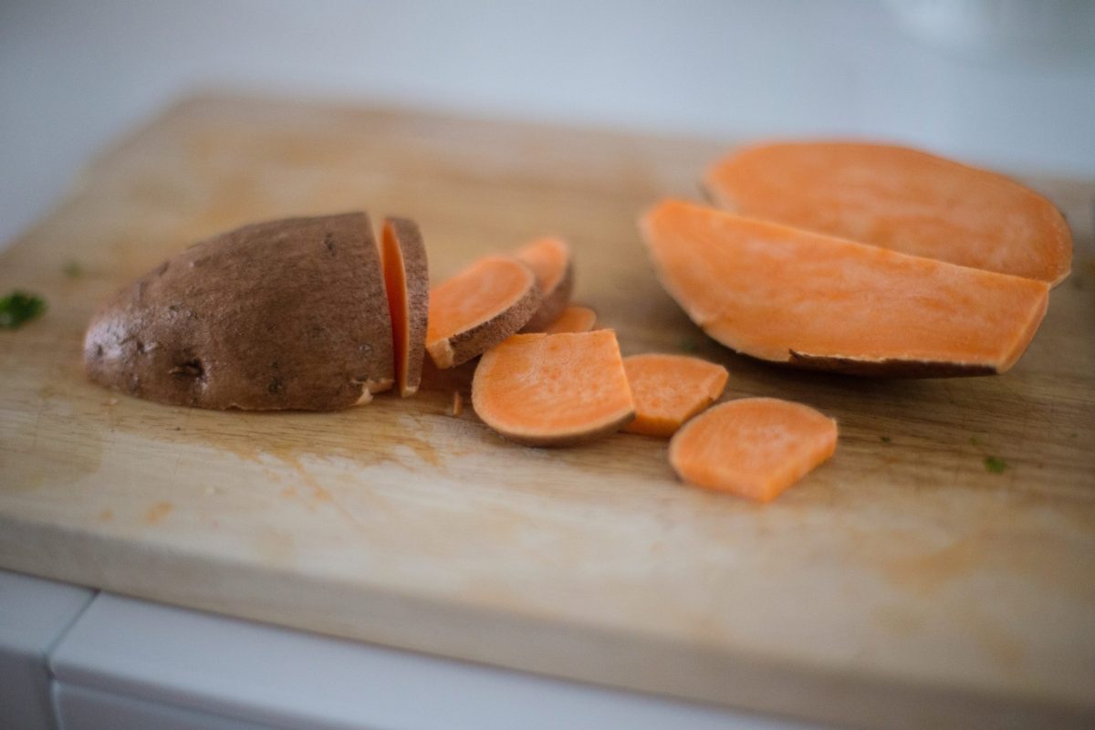 Sliced sweet potatoes sit on a cutting board.