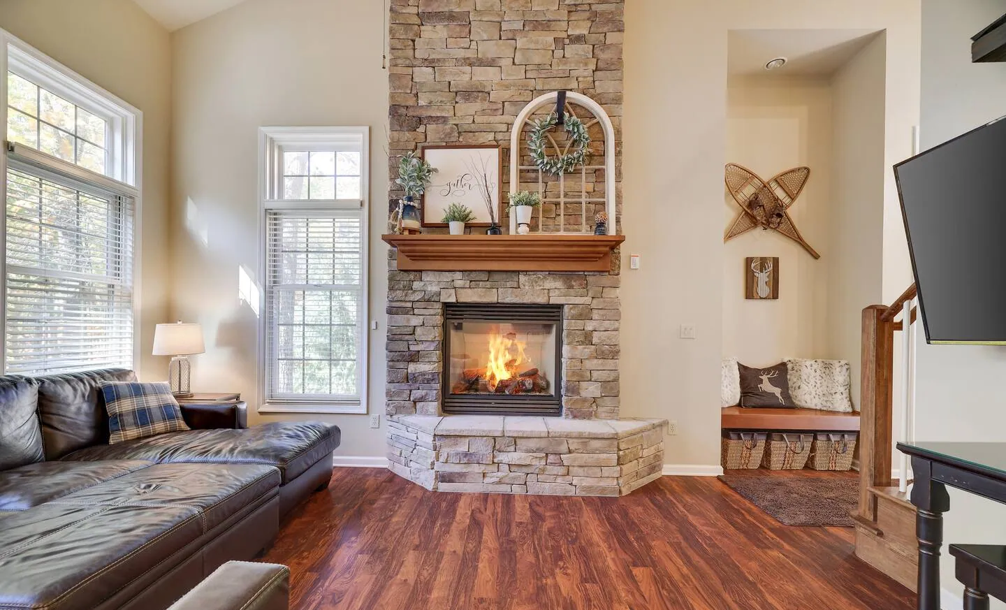 Stone gas fireplace with leather sectional and snowshoe decor at Mountainwoods Memories