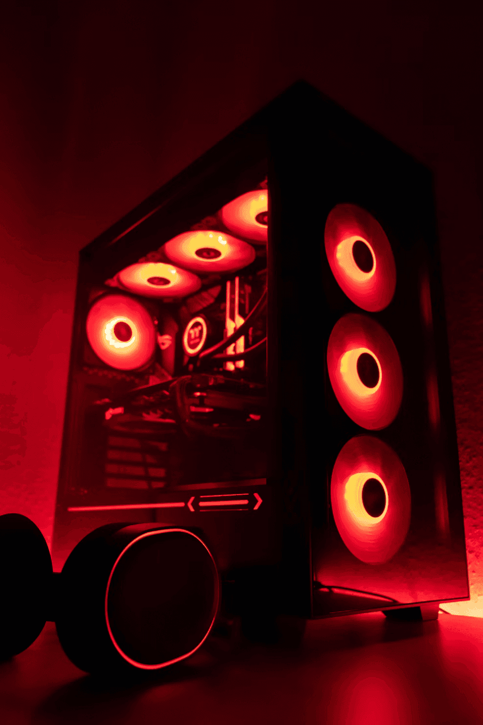 Czarno-białe, dynamiczne ujęcie komputera stacjonarnego PC Gaming z podświetlanymi wentylatorami i słuchawkami na pierwszym planie. Po najechaniu myszką obraz zmienia barwę na niebiesko-zielony cyjan.