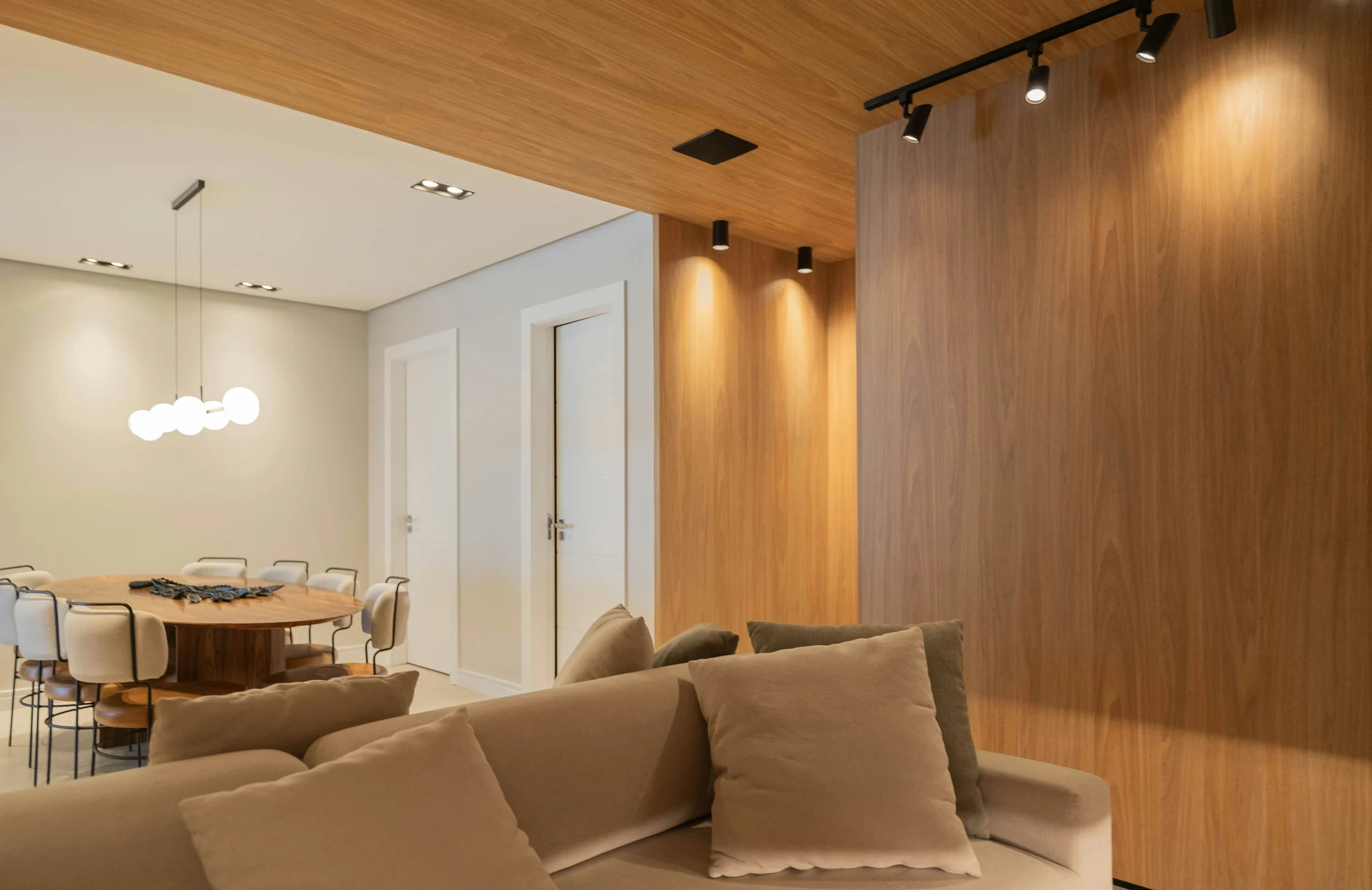 Minimalist living space featuring oak flooring, timber wall panels and panoramic windows with natural light.