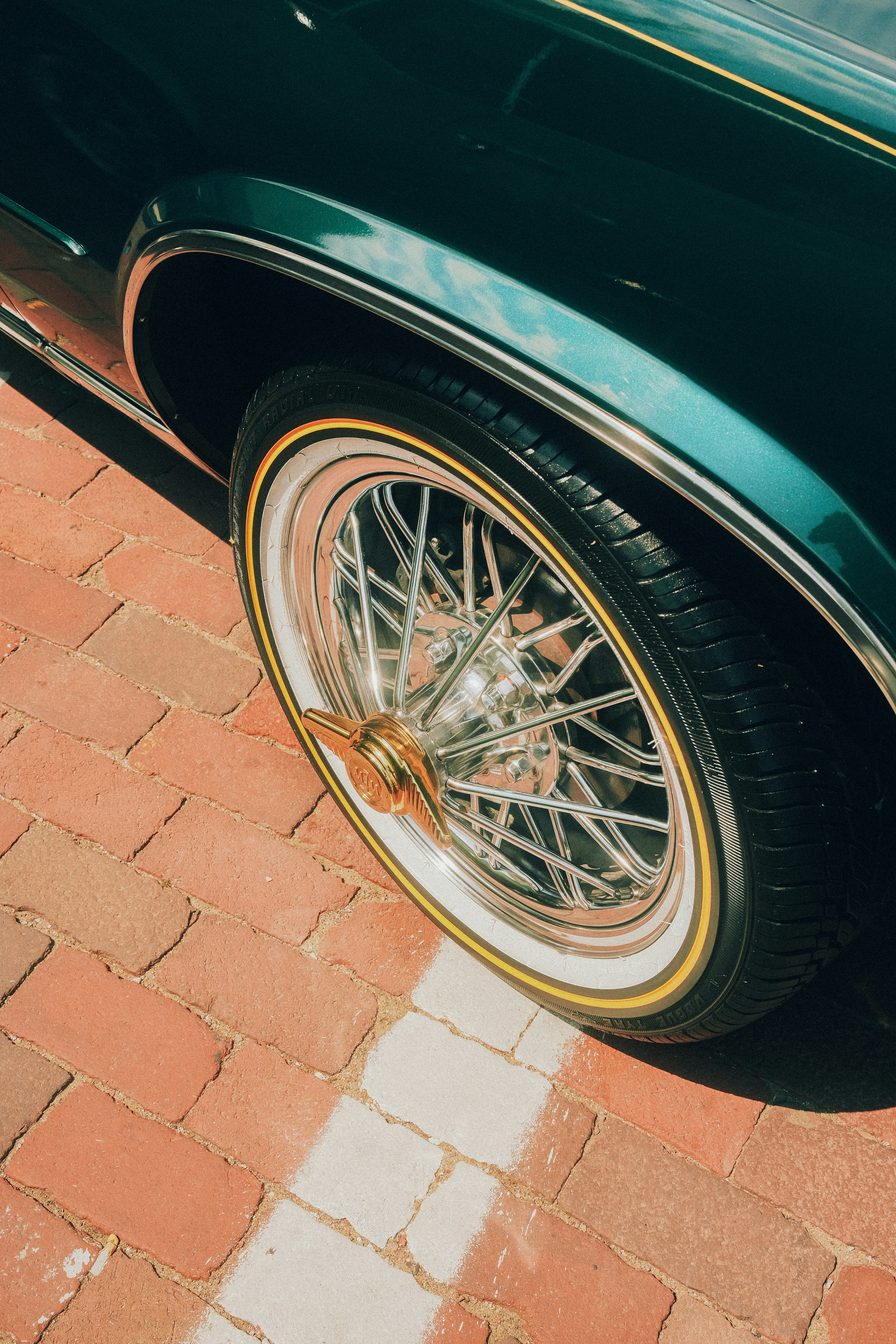 Close-up of a vintage car wheel on brick pavement