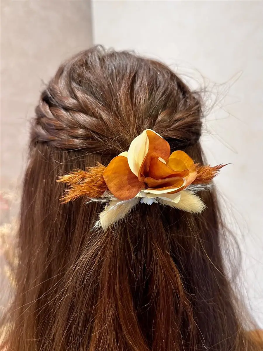 Pince à cheveux en fleurs séchées dans une coiffure tressée