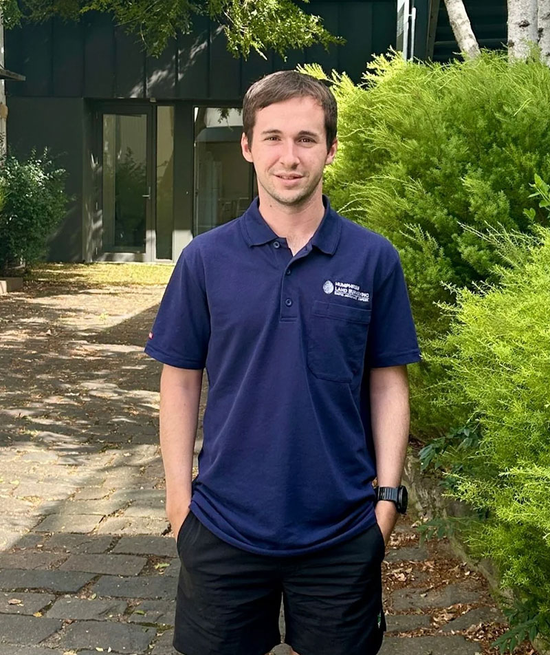 A profile image of Brad Percey in a professional surveyor uniform in a leafy outdoor setting