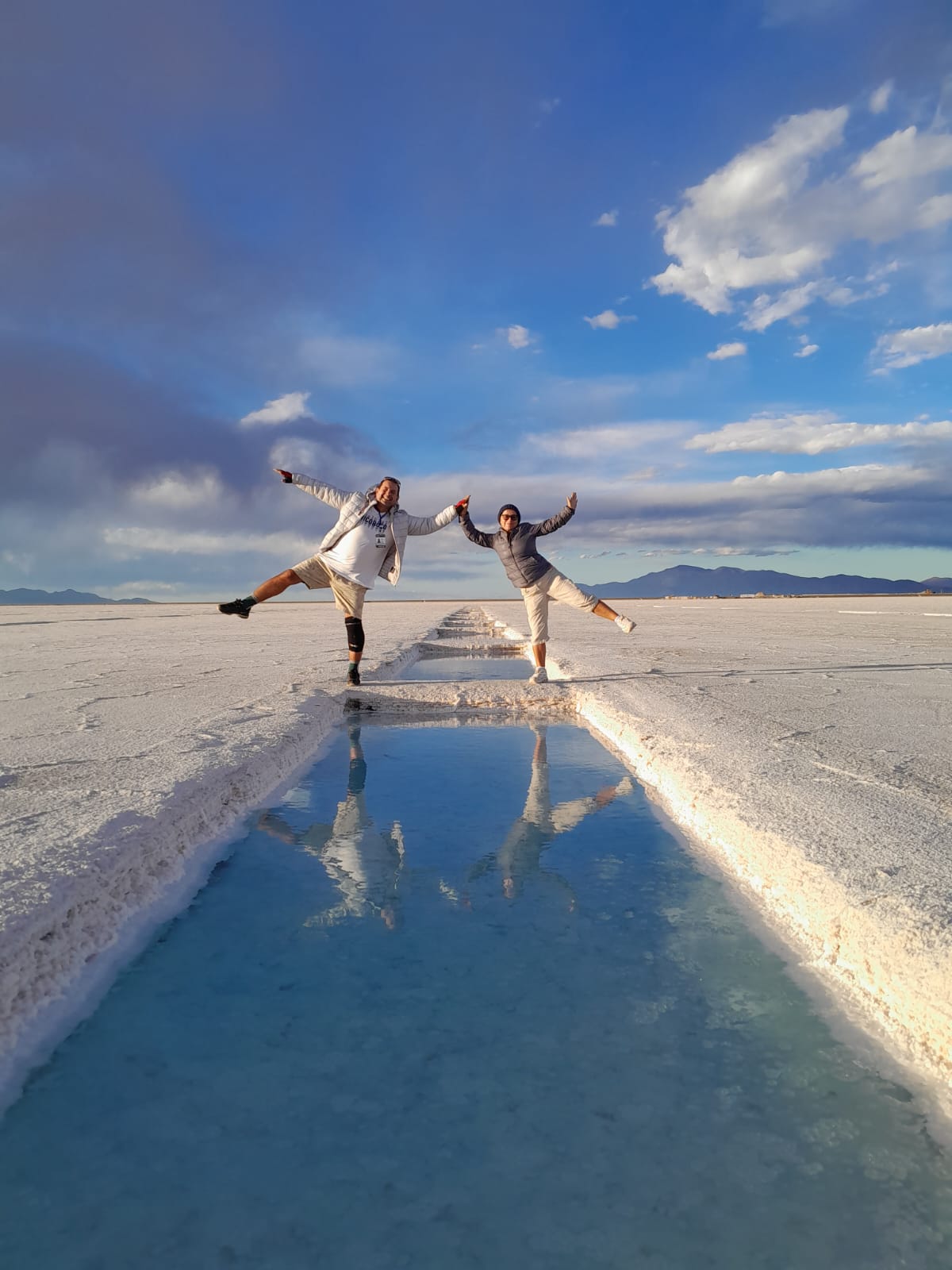 Mujer sentada sobre un tronco frente a una cascada doble en un bosque frondoso de Argentina.