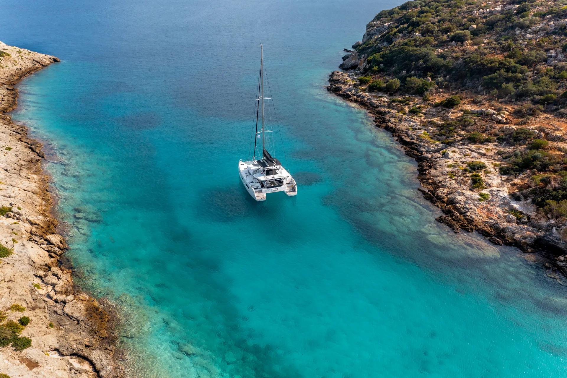 White Rock 36 speedboat with captain at helm cruising calm blue waters near Paros coastline with hills in background.