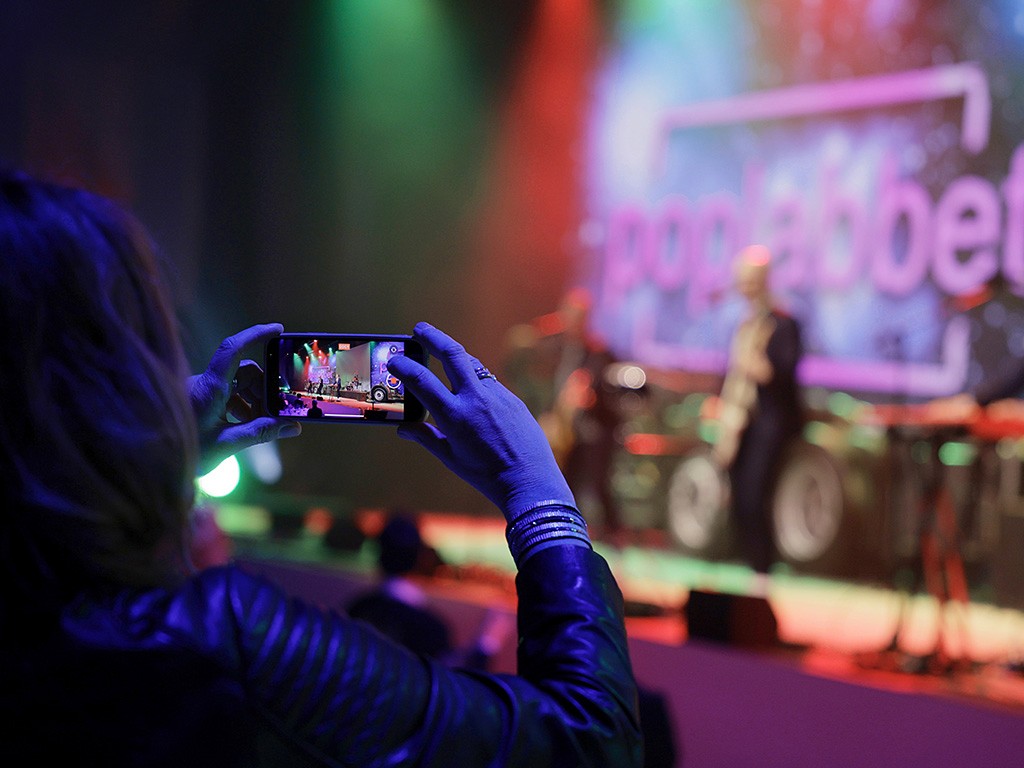 En kvinna som tar en bild av ett band på en scen med sin telefon