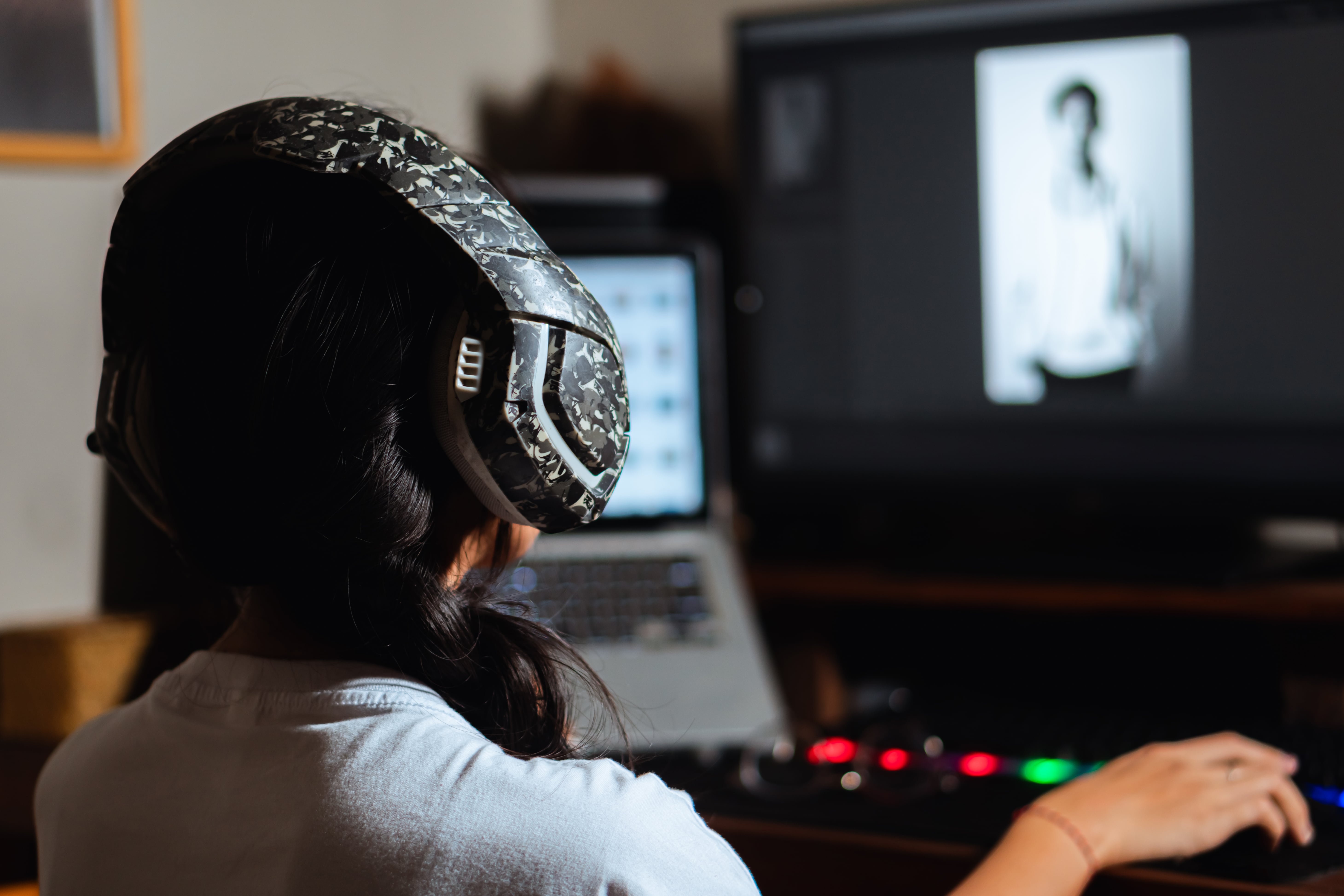 Woman wearing headphones editing black and white photo on computer using photo editing software