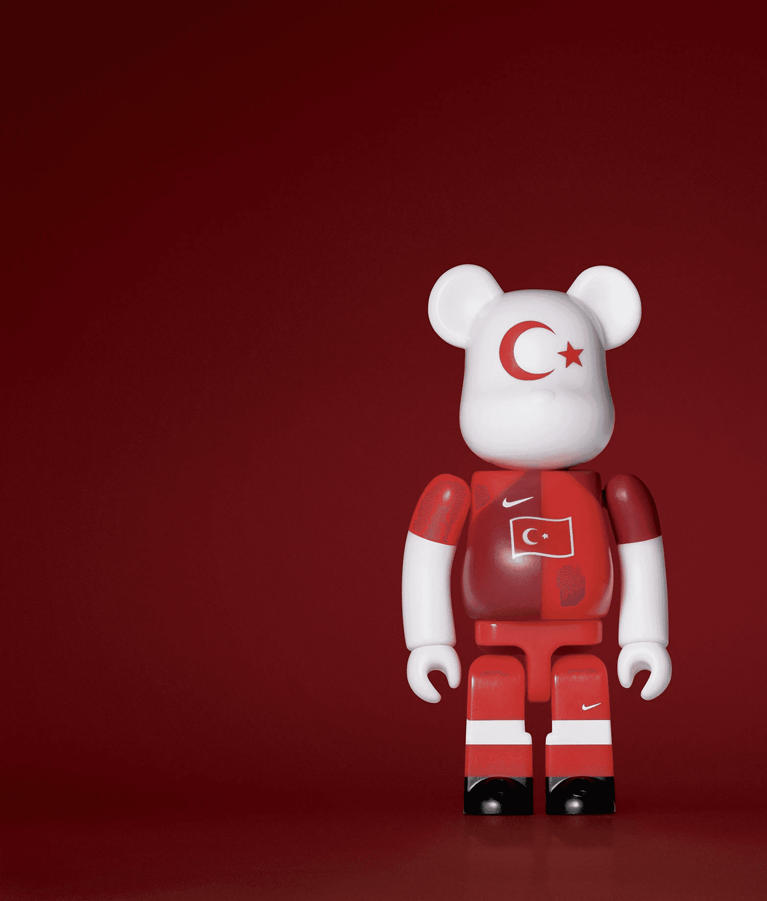 A single 3.5” tall Bre@rbrick/Nike toy created to commemorate the 2006 Turkish World Cup football team. The toy is painted to appear in the Turkish football kit and stands in the center of the frame in front of a dark red background.