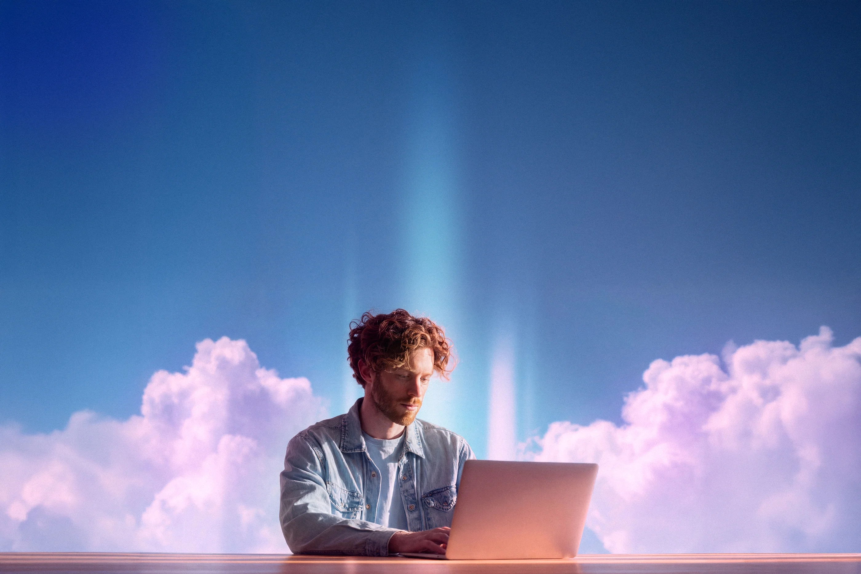 Person using free screen recorder with laptop against blue sky and purple clouds