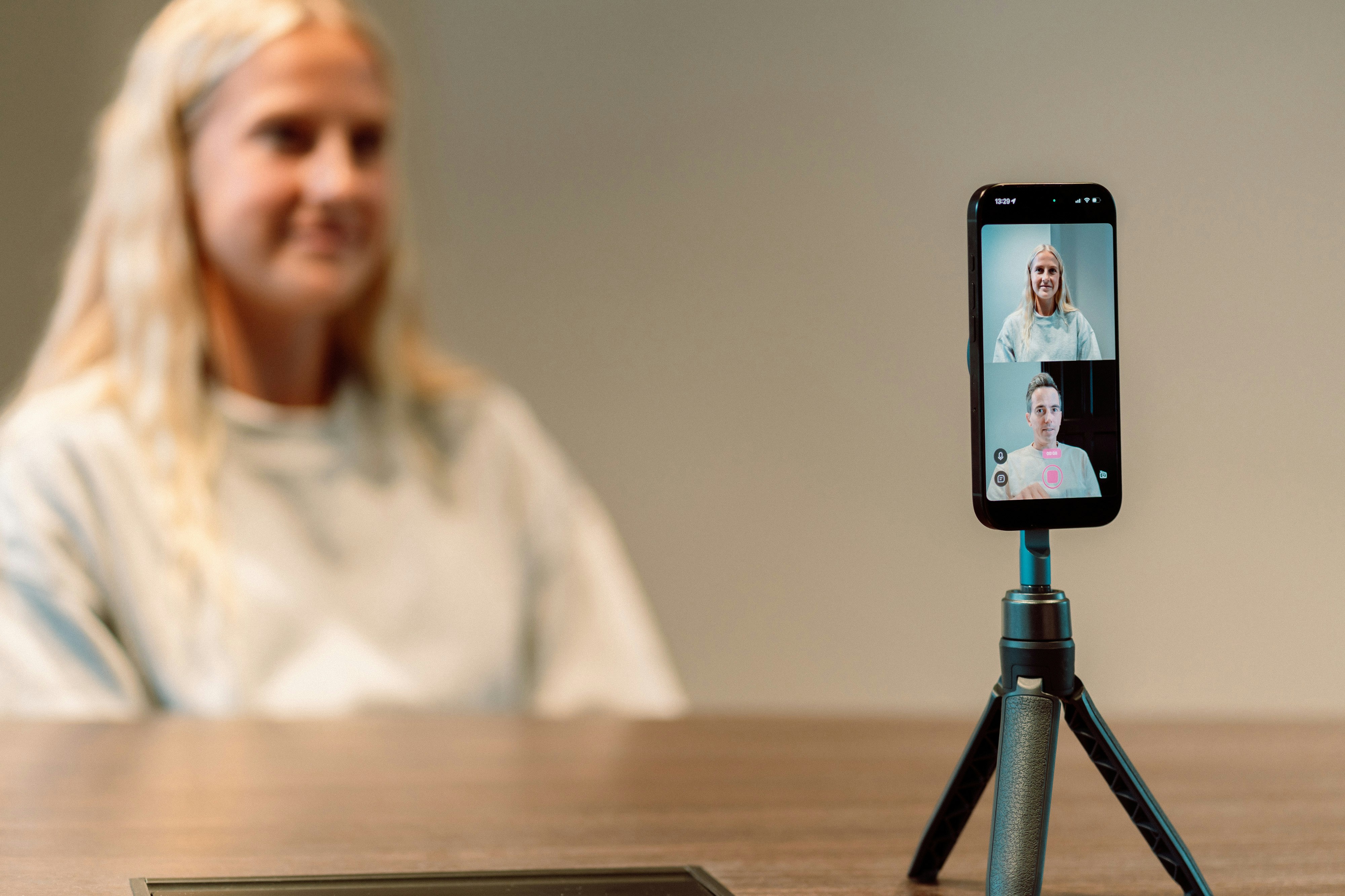 Candidate preparing for AI video interview with smartphone mounted on tripod showing proper camera setup and professional environment