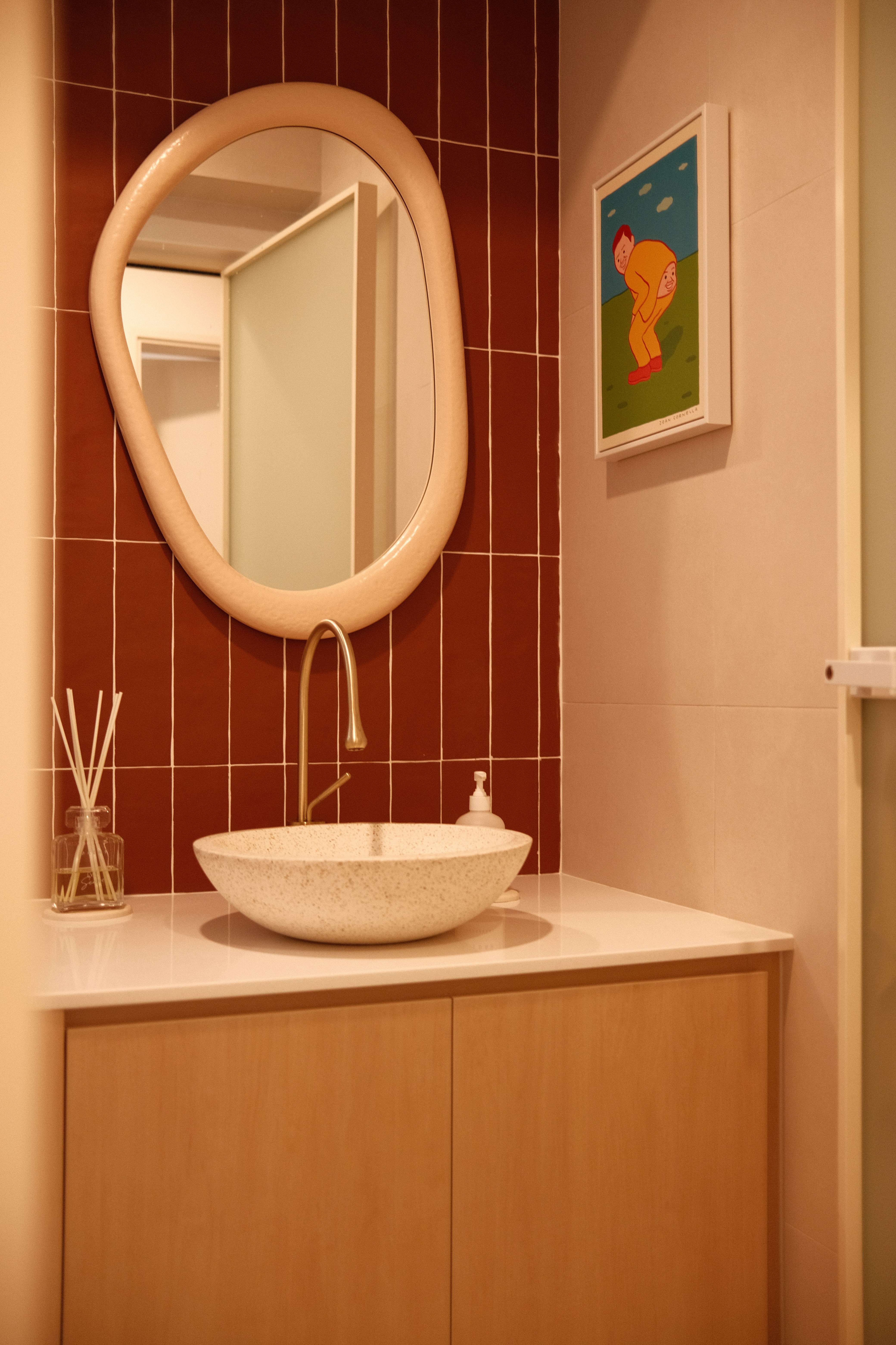 Modern powder room with organic-shaped mirror, statement red wall tiles, and vessel basin in Tampines Wabi-O by Singapore interior designer.