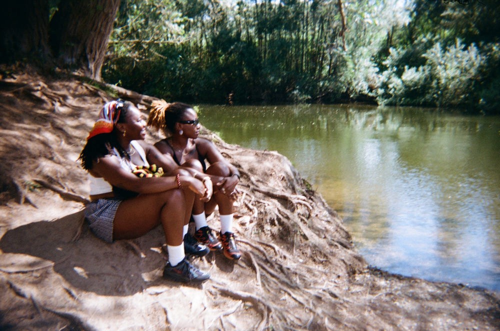 A woman gets her hair done by another woman whilst sat outdoors