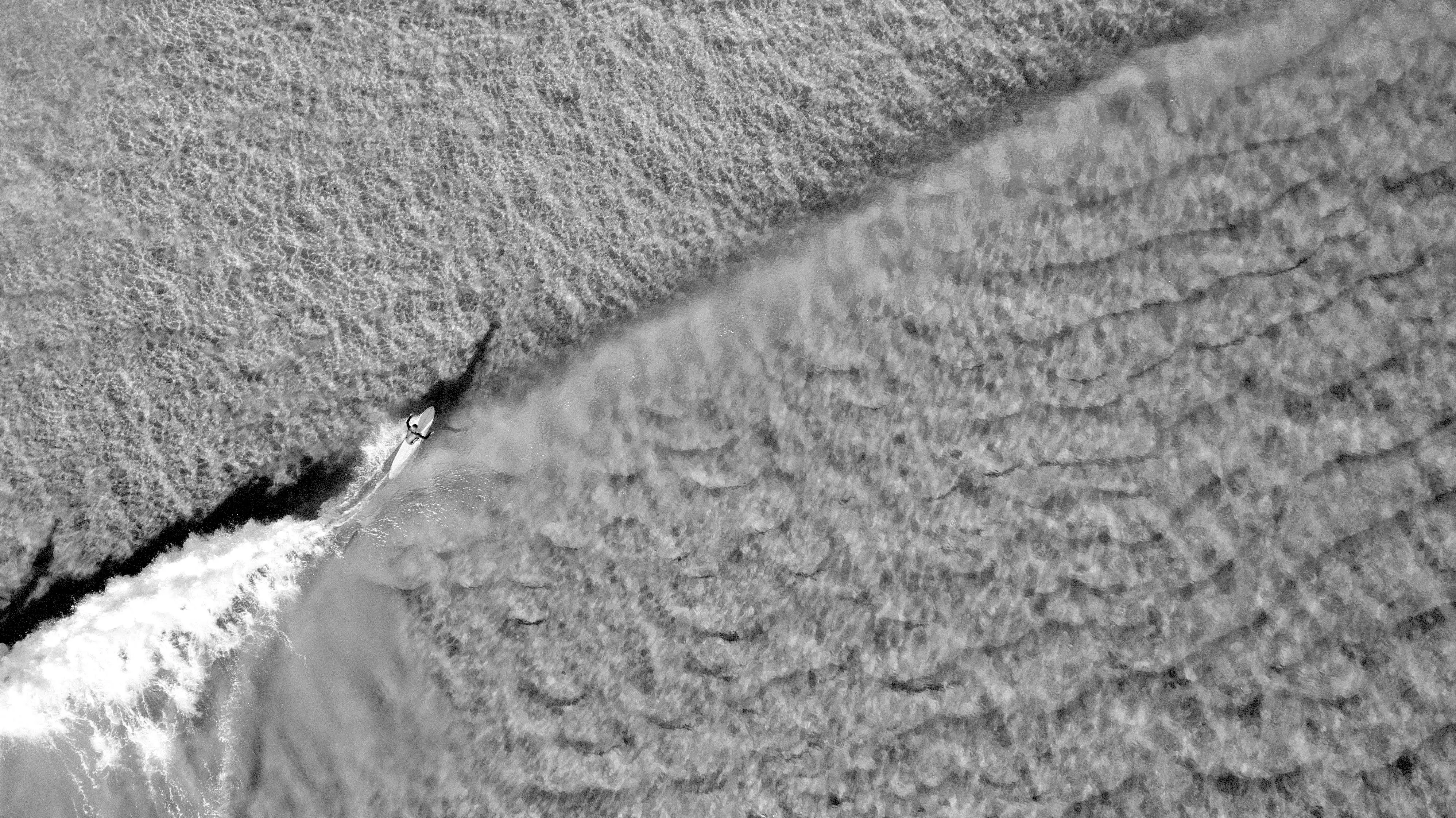 Private jet charter flights Byron Bay - Private jet flying over the coastline near Byron Bay, New South Wales, Australia, one of the most popular luxury travel destinations on Australia’s east coast. The view of a surfer below