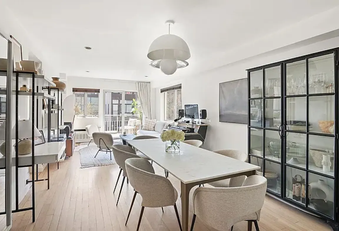 A dining room featuring a wooden table surrounded by four chairs, with soft lighting creating a warm atmosphere.