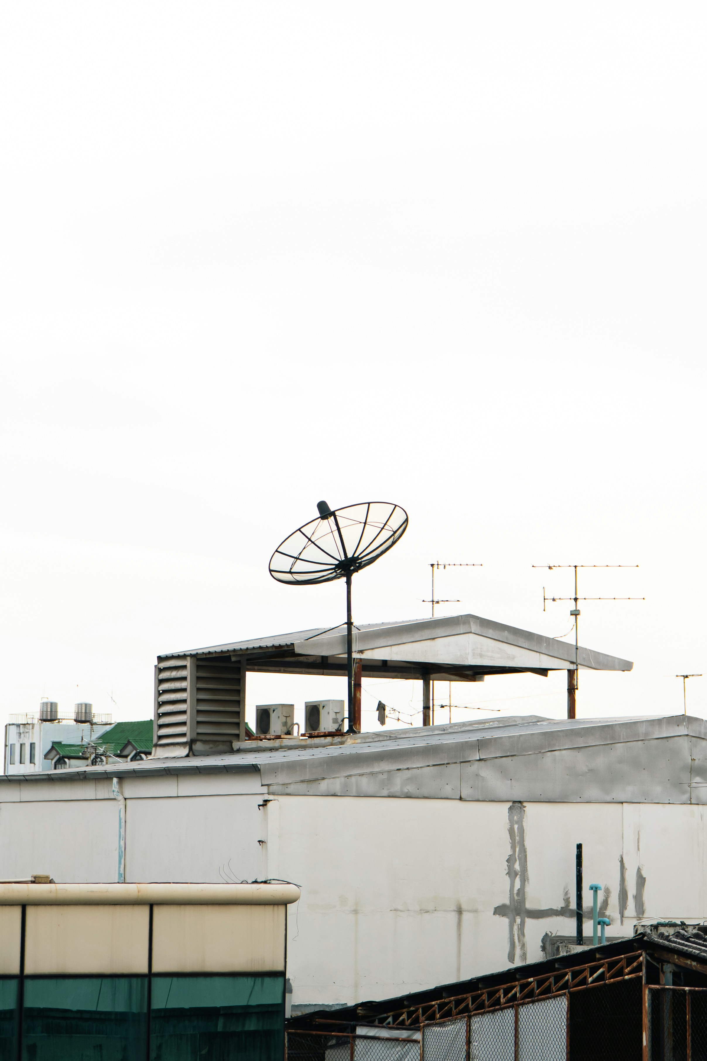 Satellite dish on a rooftop with buildings.