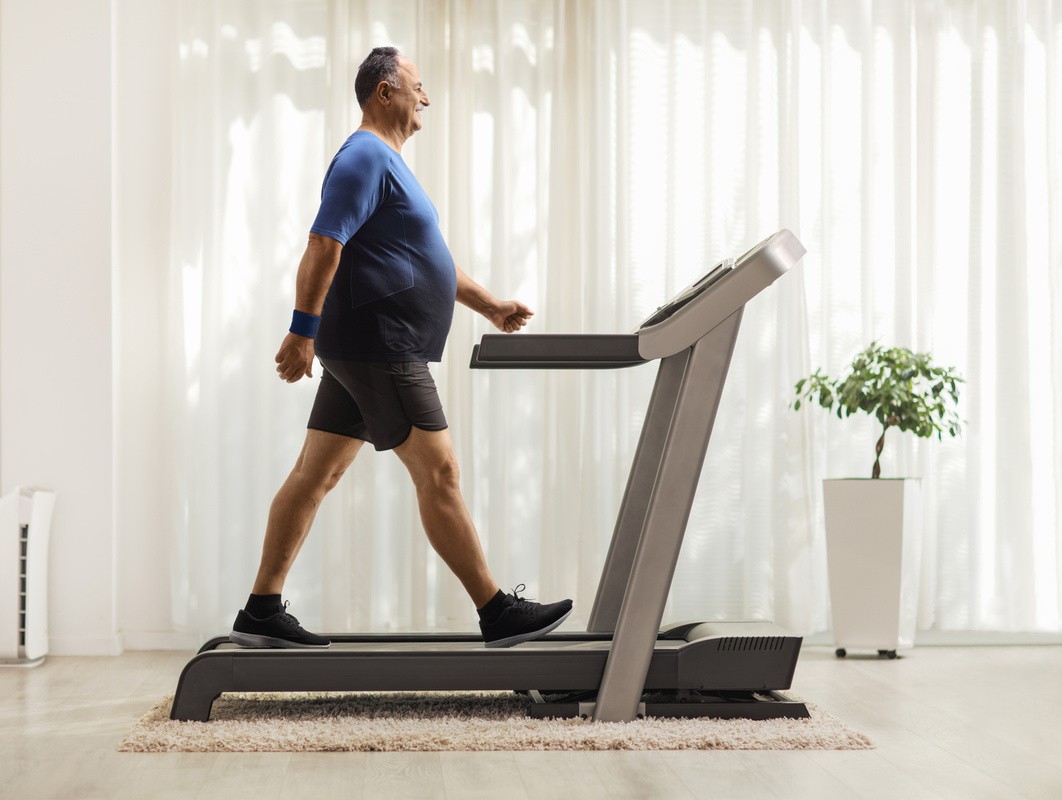 mature overweight man doing easy treadmill workouts for beginners to lose weight at home