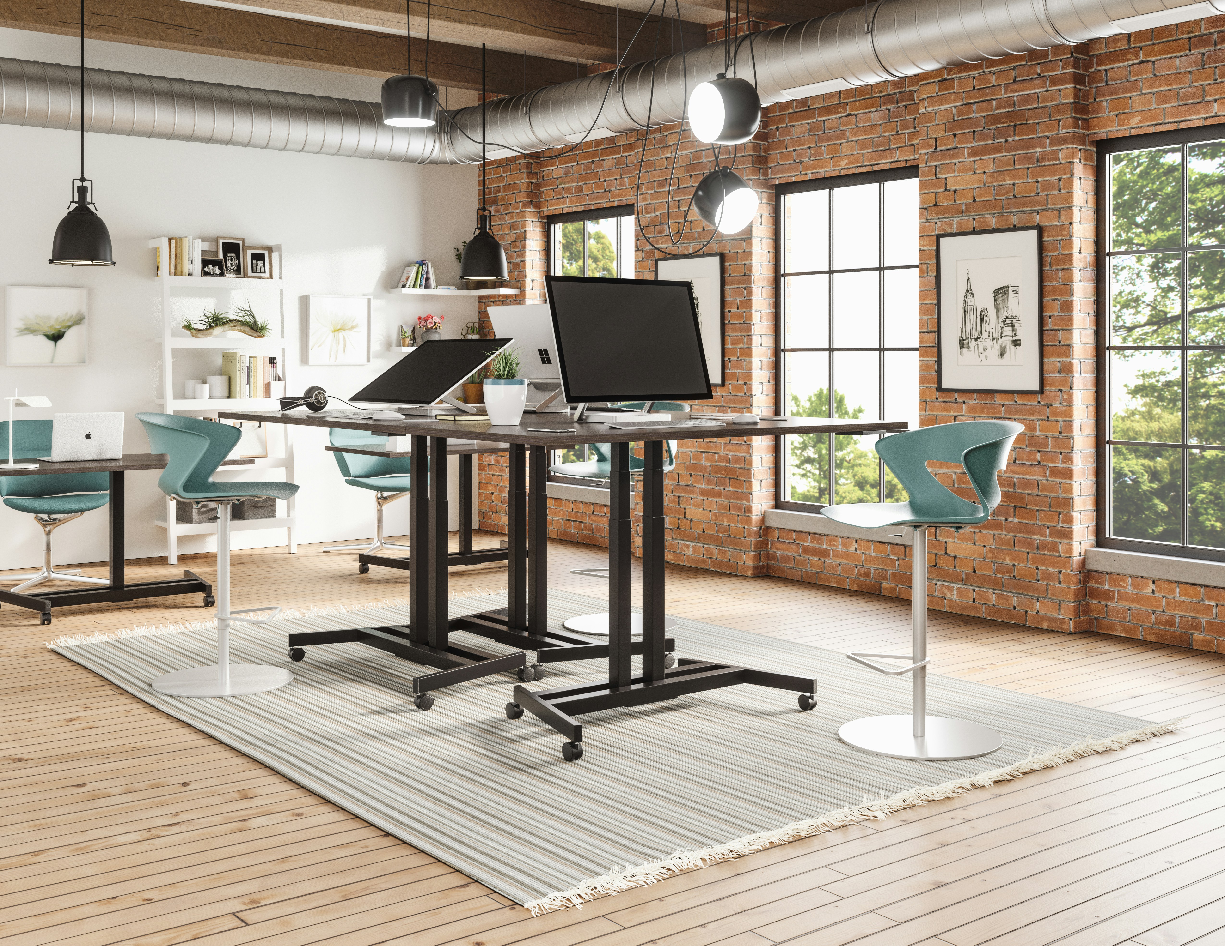Industrial loft office with teal chairs, exposed brick, and adjustable standing desks