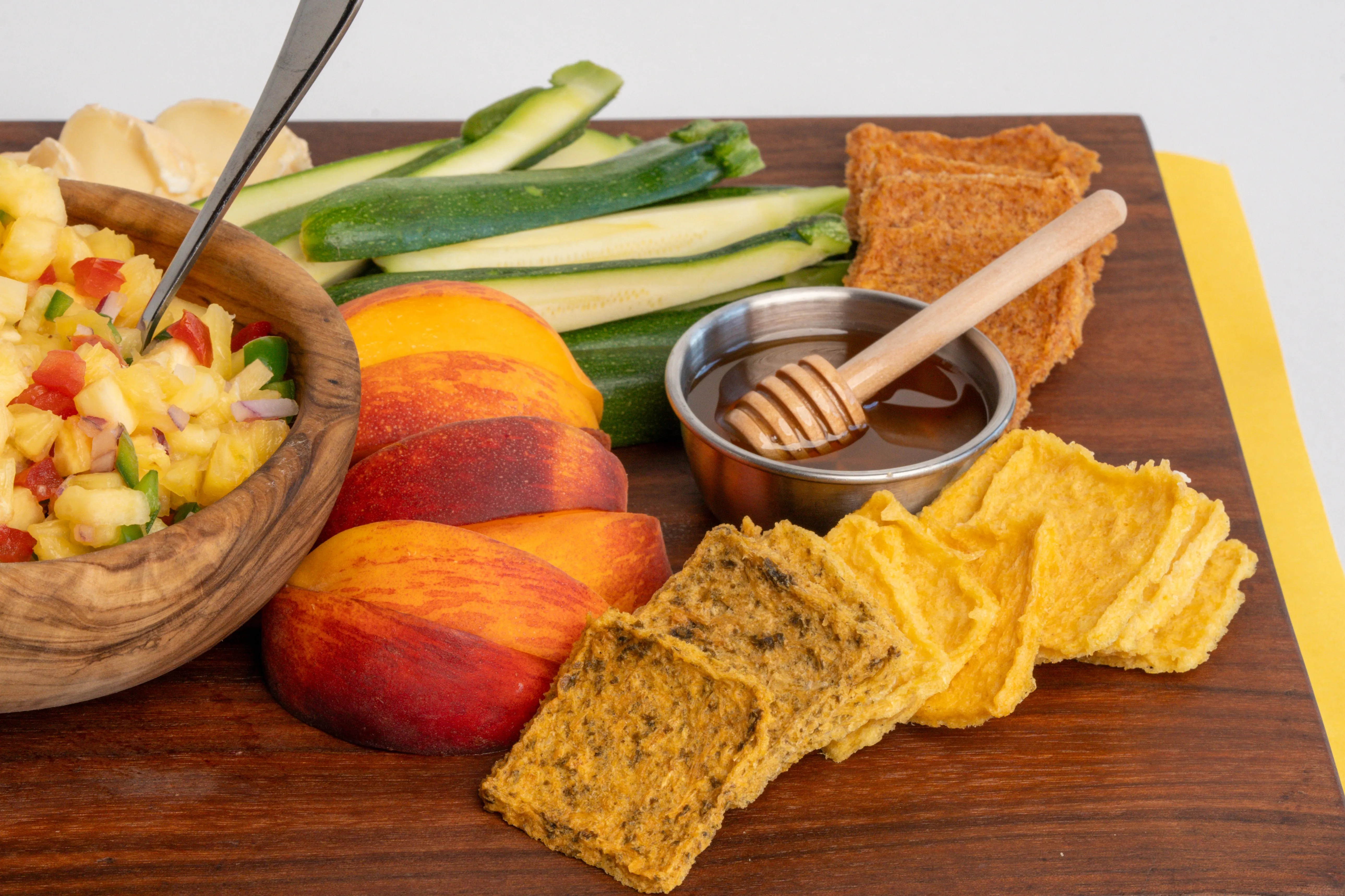 Fresh summer snack board with peaches, zucchini, honey, and crackers. Healthy appetizer idea.