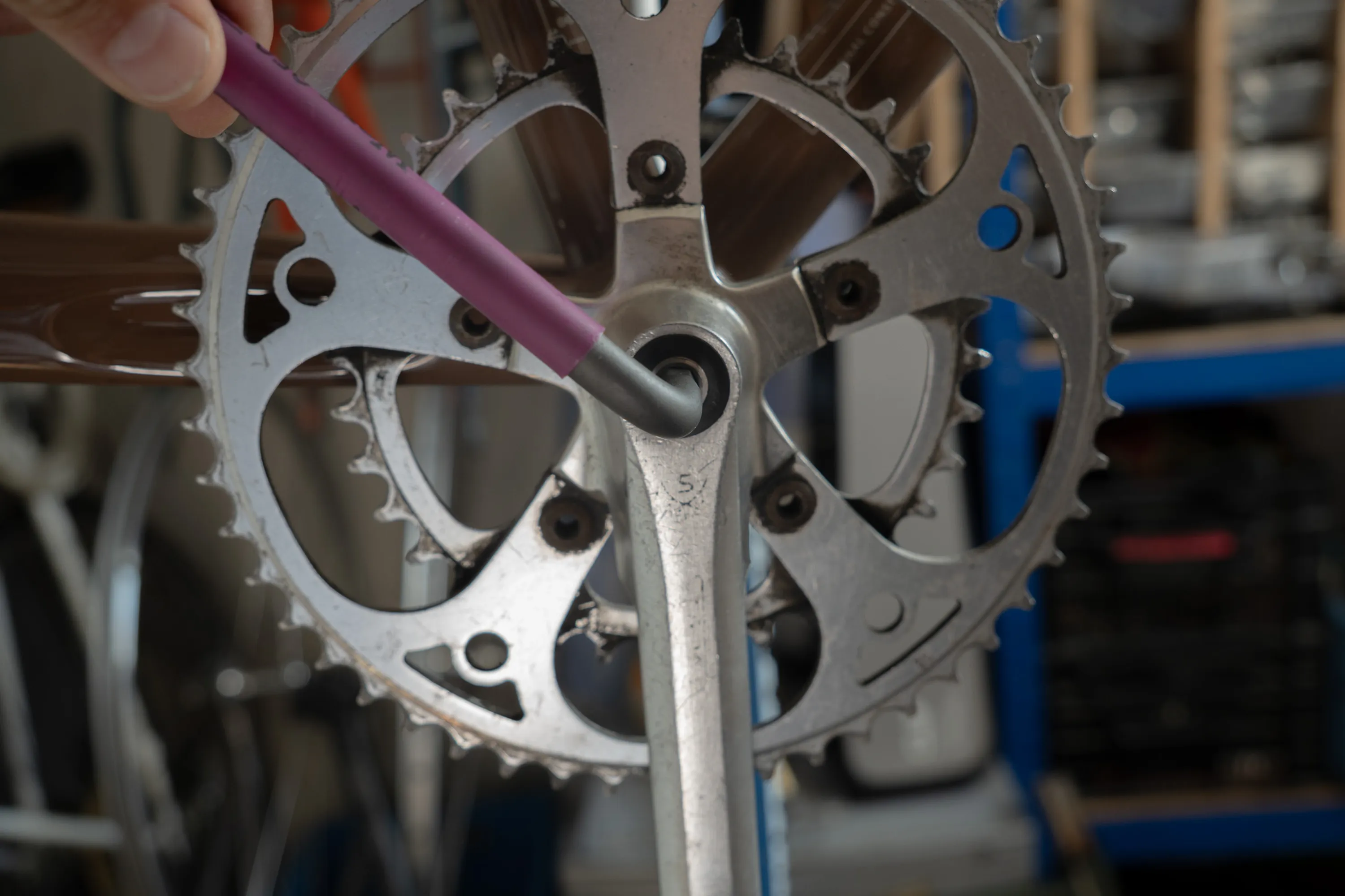 A close up of a person working on a bike crankset