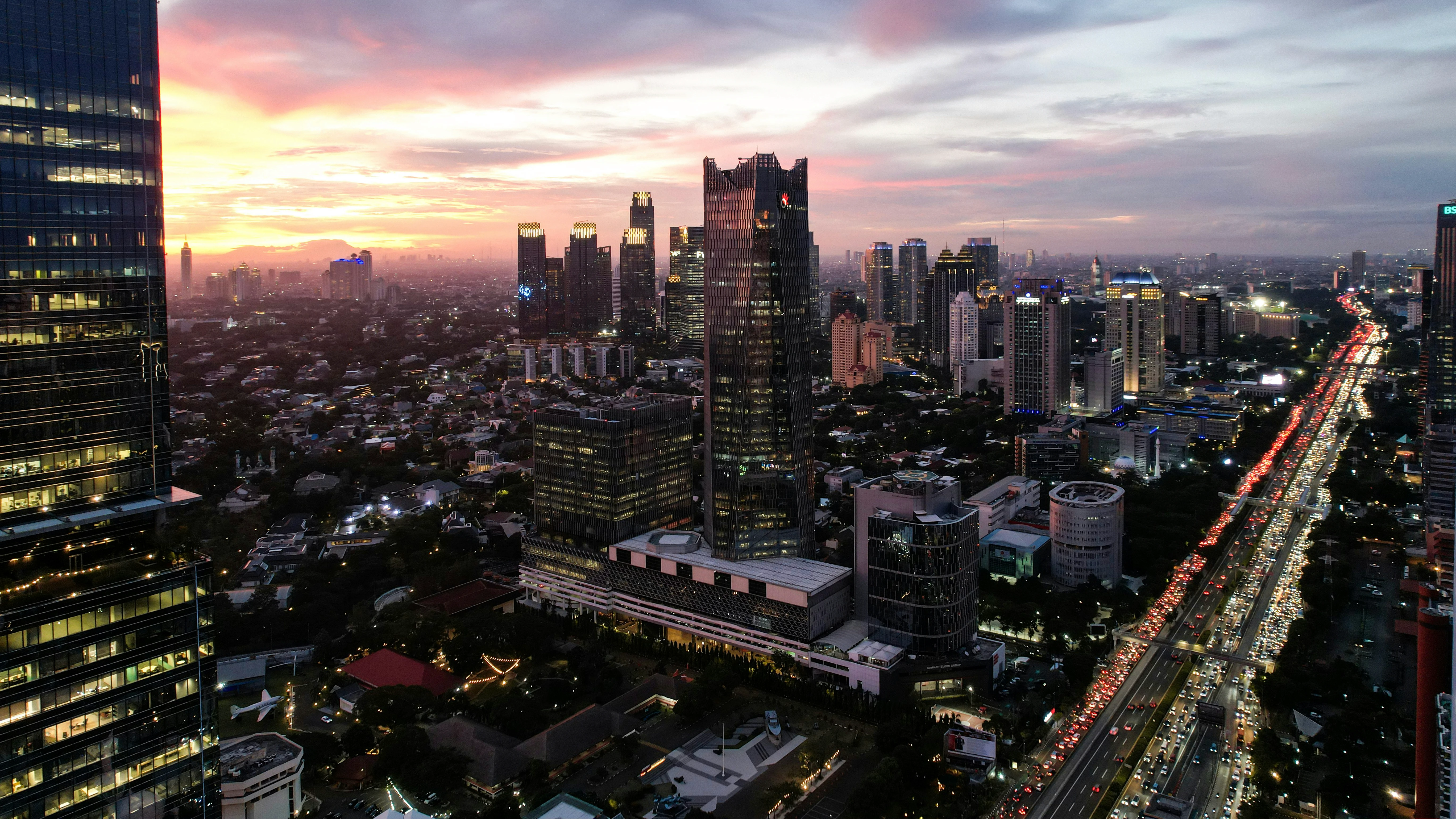 A Filipino city skyline at sunset, showcasing tall buildings and a vibrant sky with clouds.