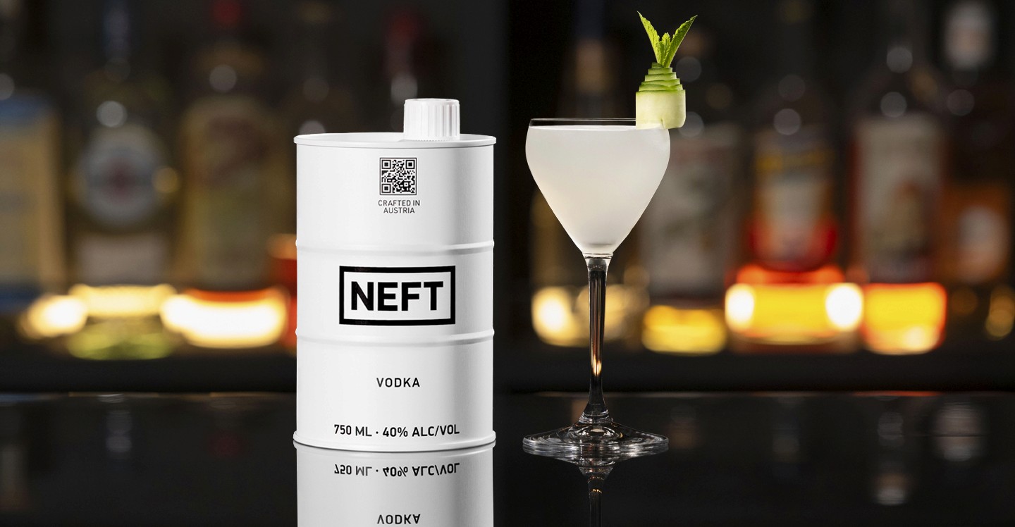 A NEFT Barrel and a glass of Cucumber Martini on a bar counter.